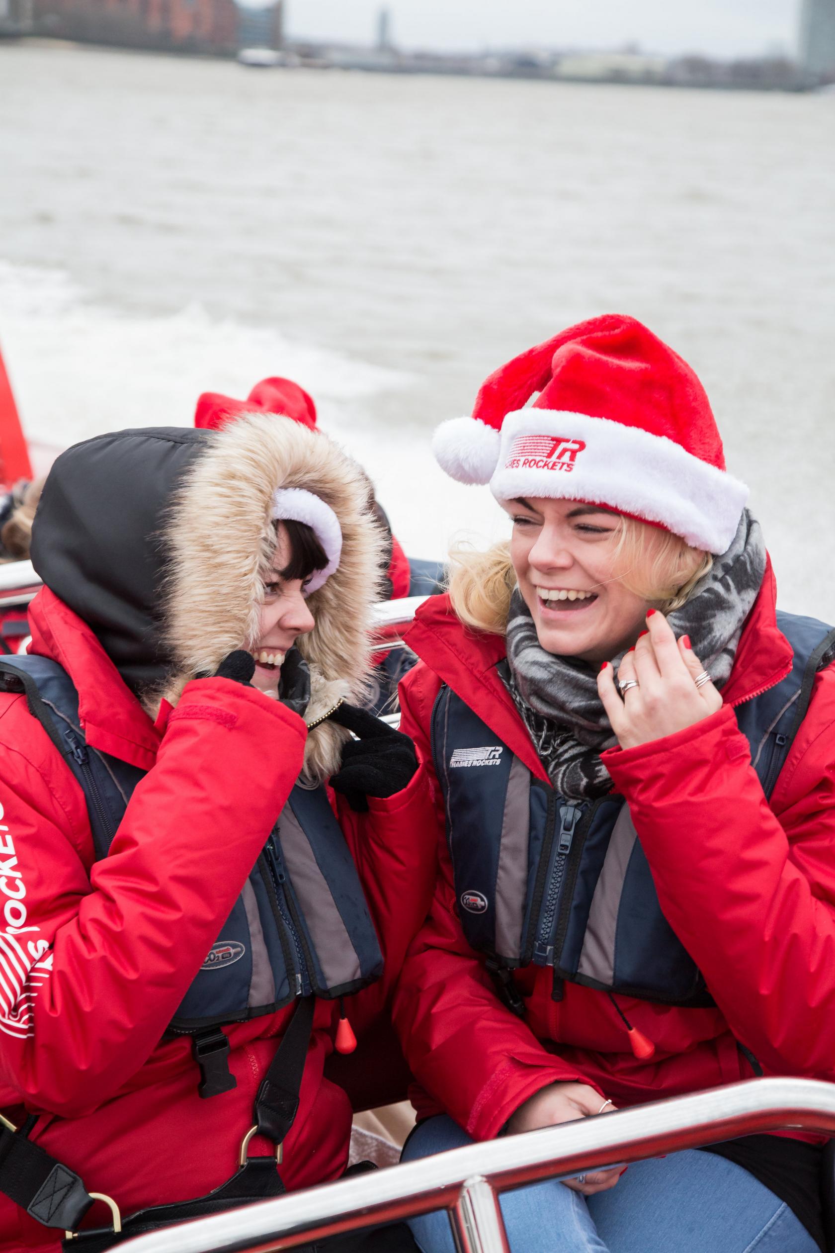 Two people in red jackets and hats with Thames Rockets logos, smiling outdoors at Thames Rockets.