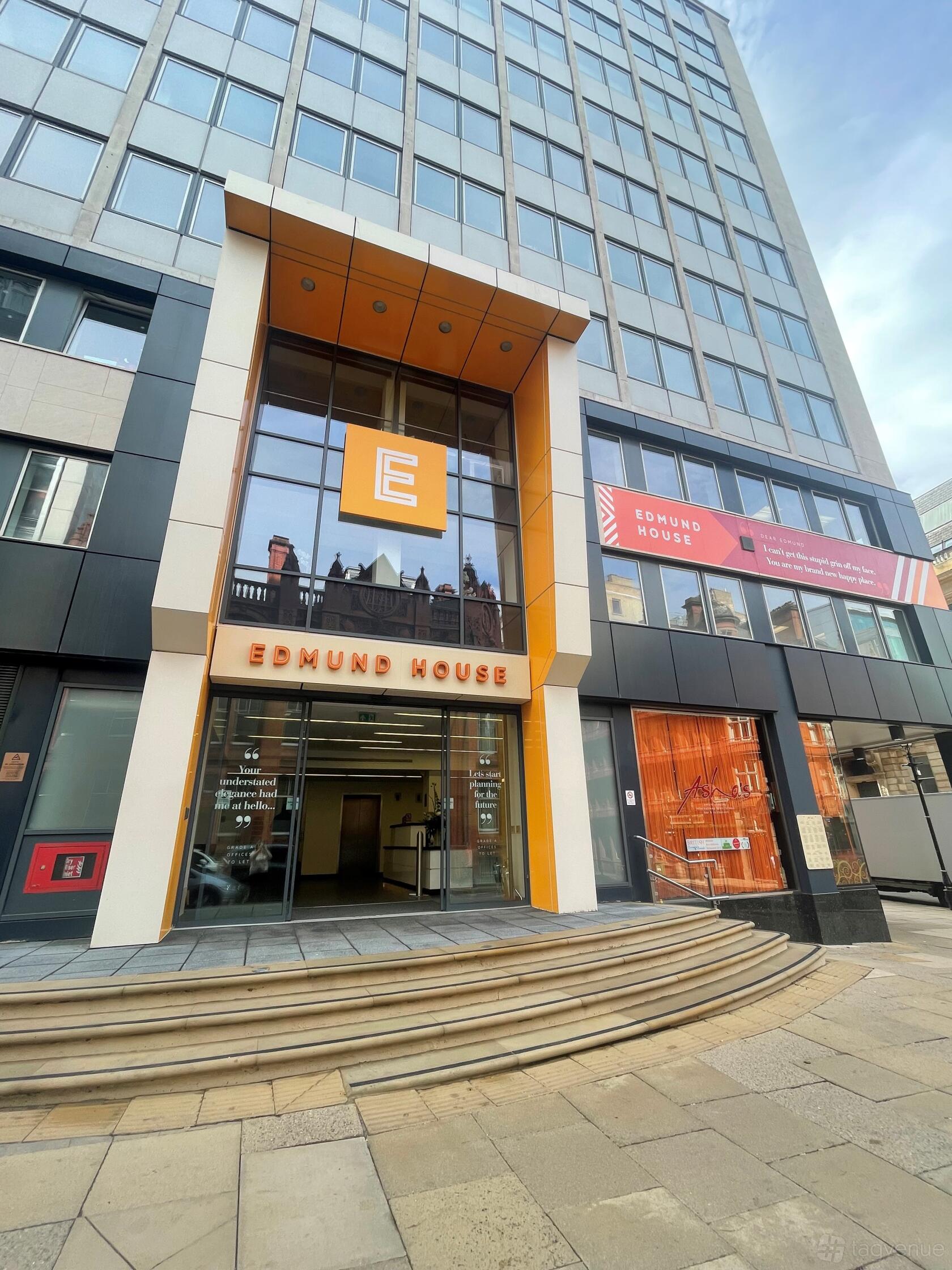 A meeting centre entrance with tall glass windows, orange signage, and street reflections at First Intuition Ltd.