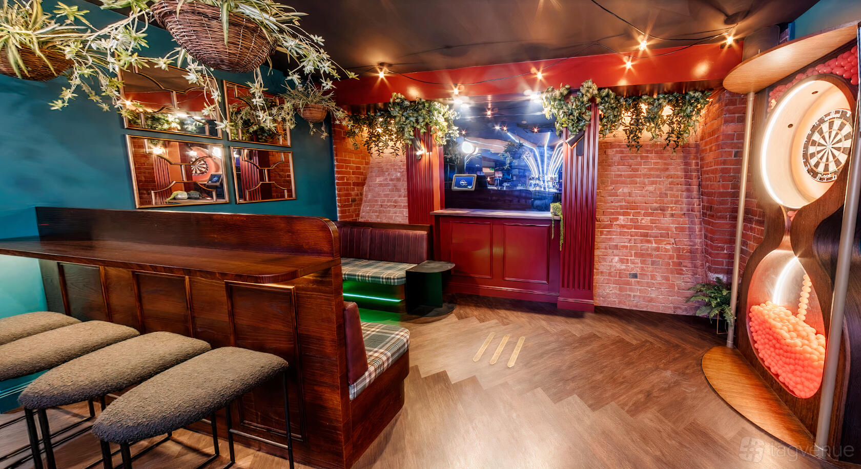 An event space in a bar with exposed brick walls, bench seating, and hanging greenery at Ballers Clubhouse Adelaide.