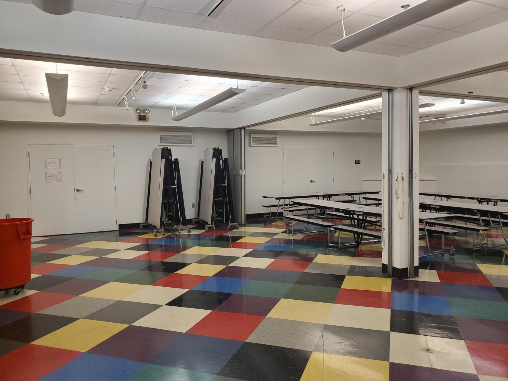 A hall with colorful checkered flooring and rows of folding cafeteria tables at Center for Puppetry Arts.