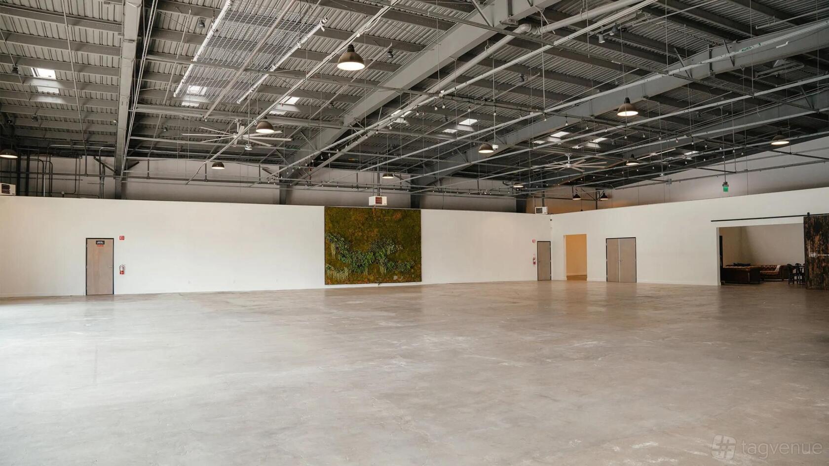 An open event venue with polished concrete floors, high exposed ceilings, and a green living wall at Rolling Greens On Mateo.