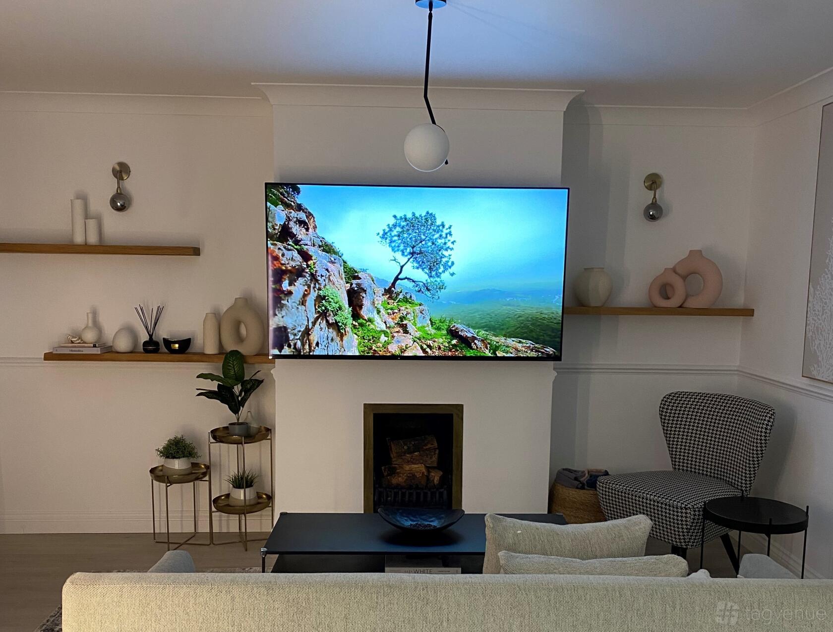 A creative space in an art studio with wall-mounted shelves, decorative vases, a large TV, and a fireplace at Creative Studio.