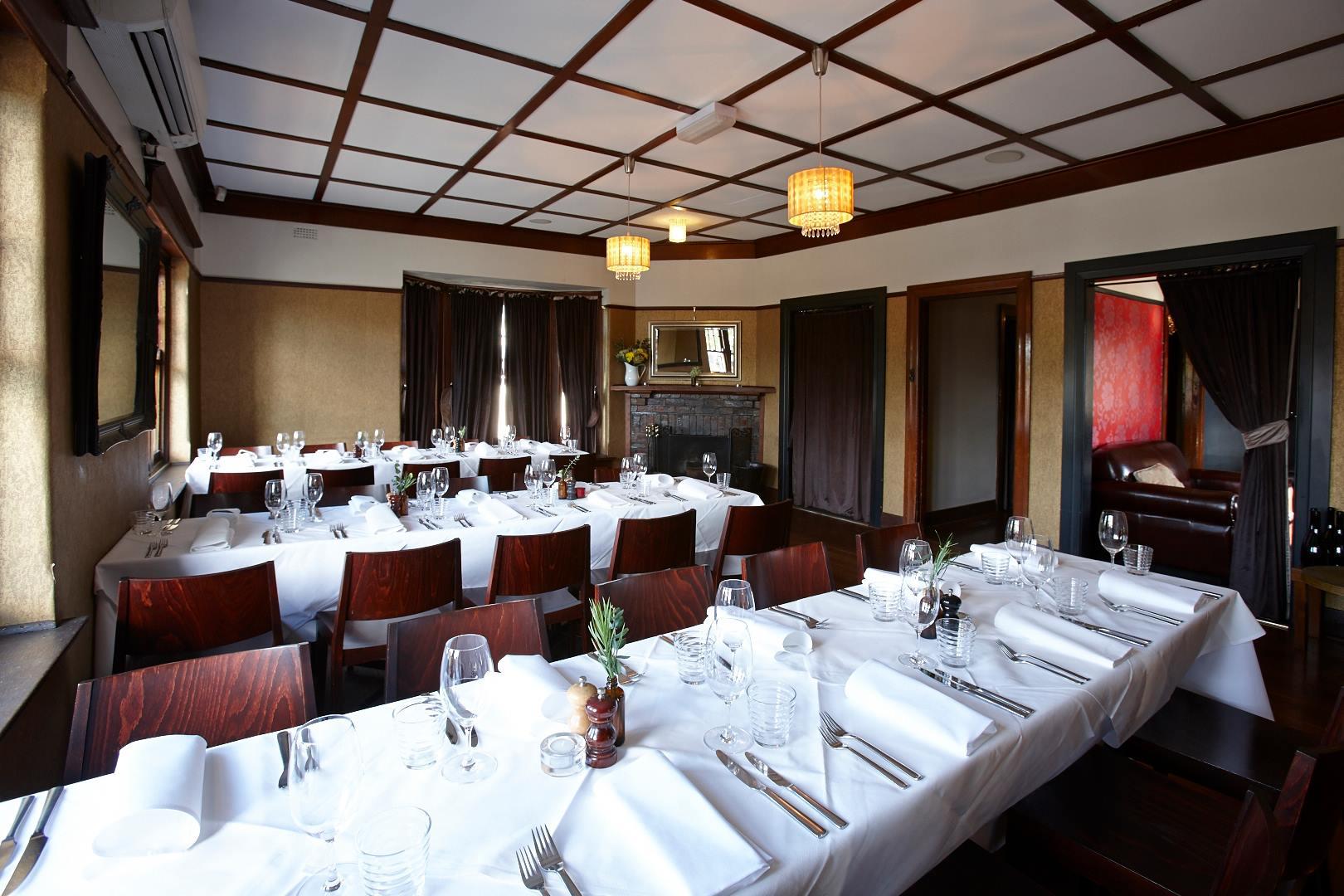 An event space with white tablecloths, wooden chairs, and a fireplace at The Firehouse.