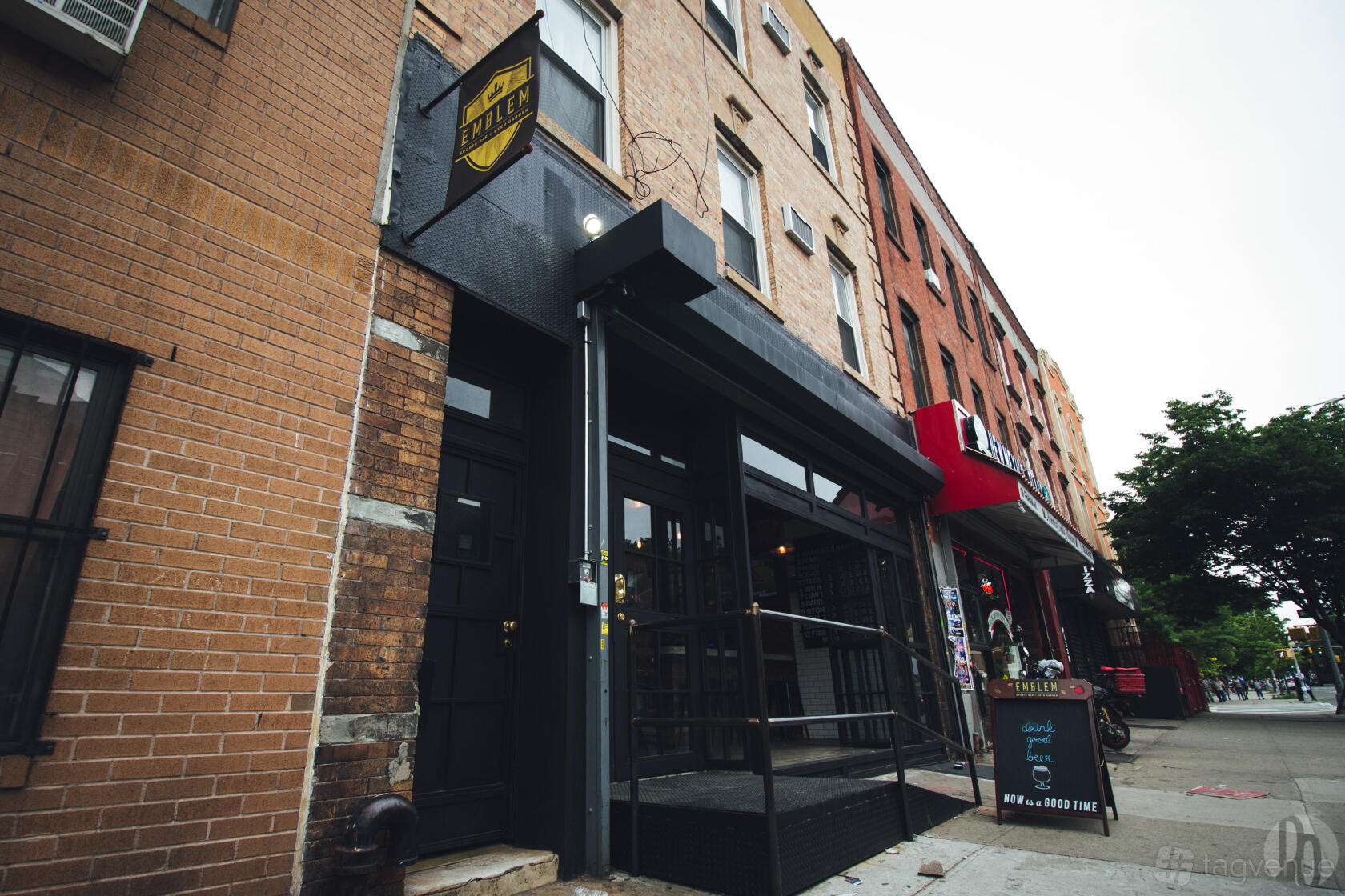 A pub with a black awning, brick exterior, and street-facing entrance at Emblem Sports Bar.