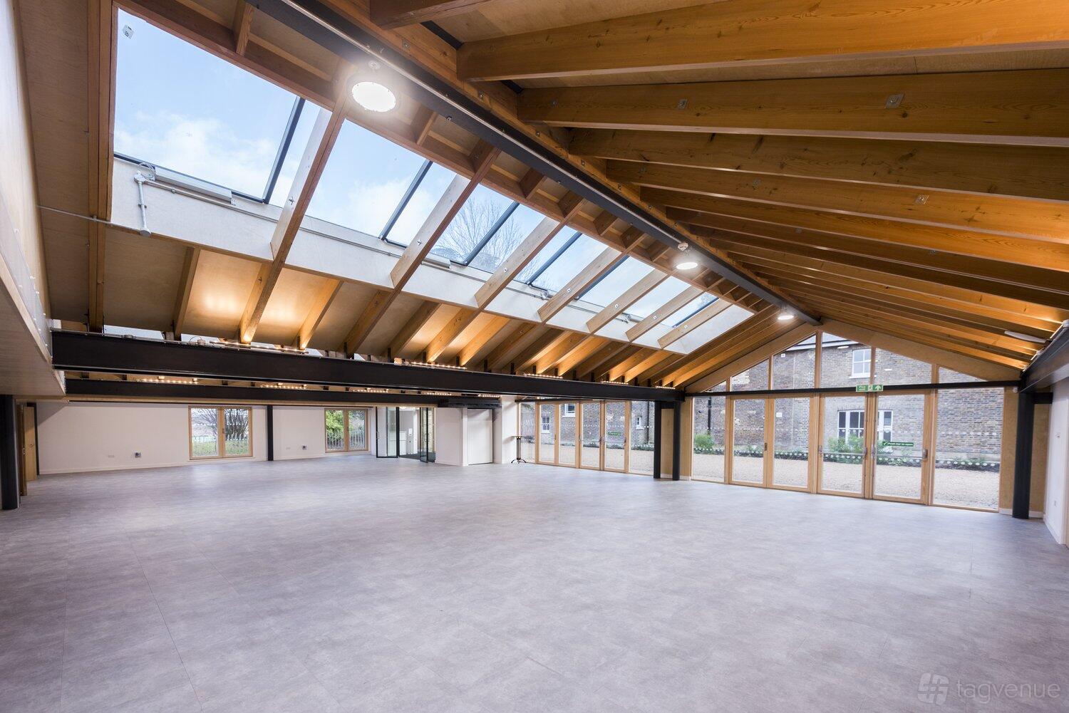 A spacious hall with exposed wooden beams, large skylights, and floor-to-ceiling windows at The Glass House - Springfield Park.