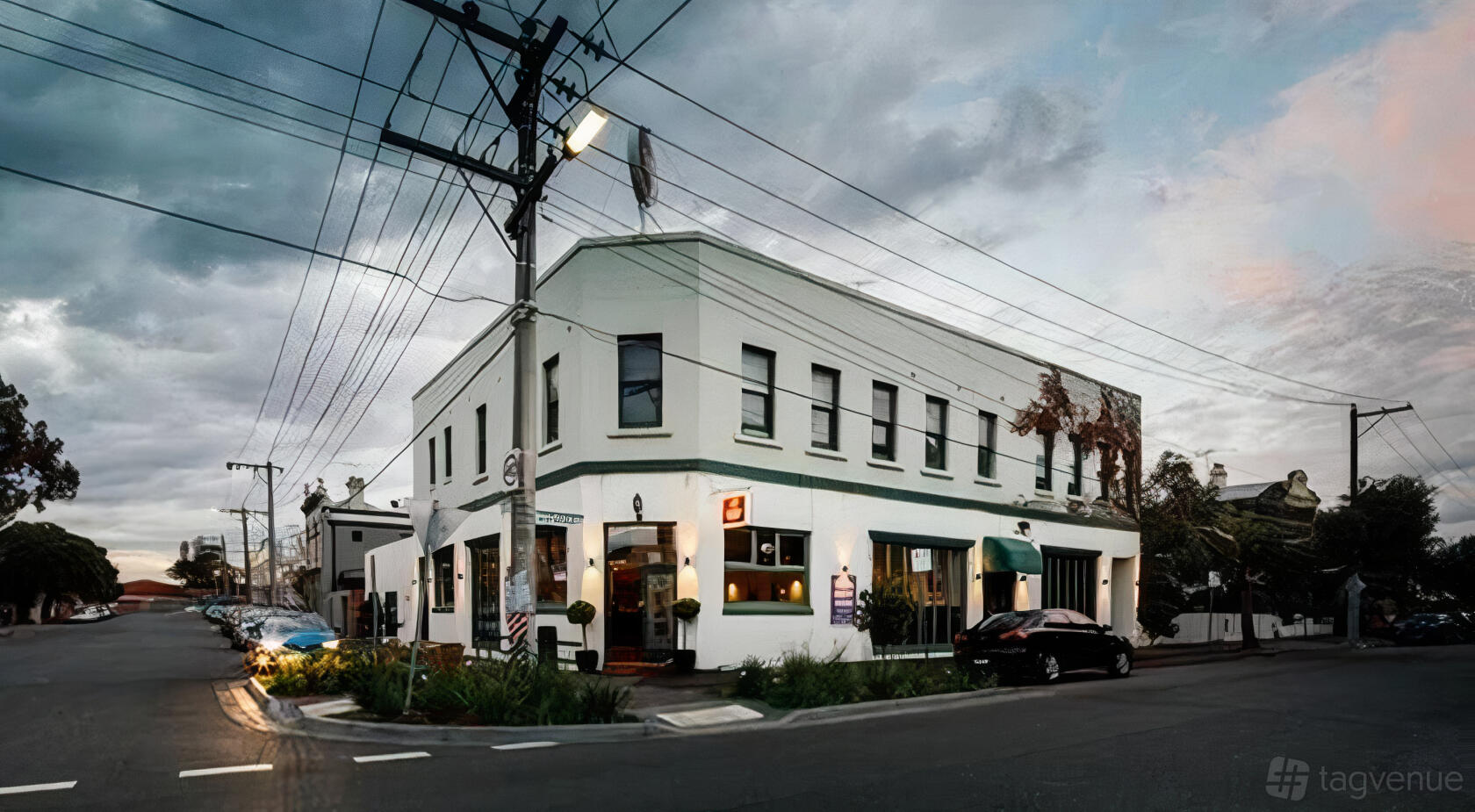 A white corner pub with large windows, green awnings, and street parking at North Port Hotel.
