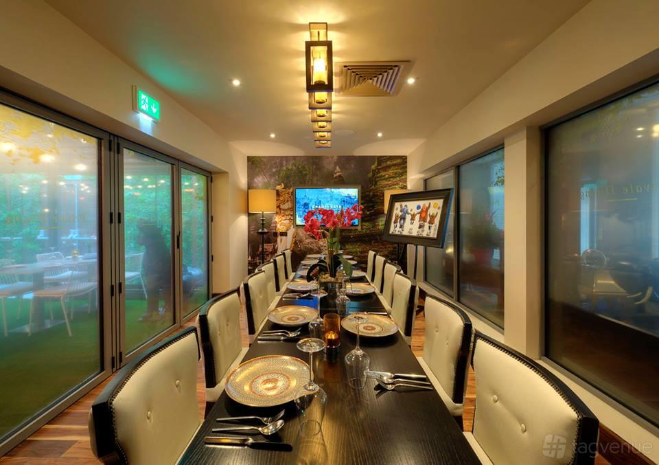 A dining room with a long black table set with decorative plates and cushioned chairs at Chaophraya Newcastle.