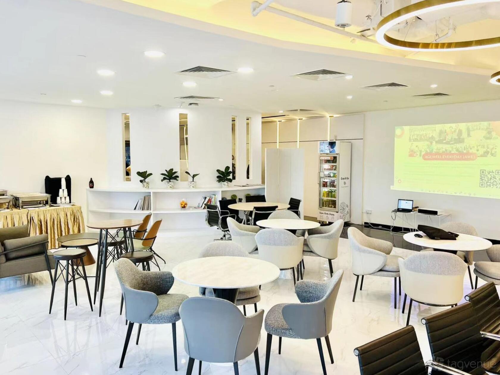 An event hall with round marble tables, cushioned chairs, white walls, and a projector screen at UCLUB CENTRAL PTE LTD.