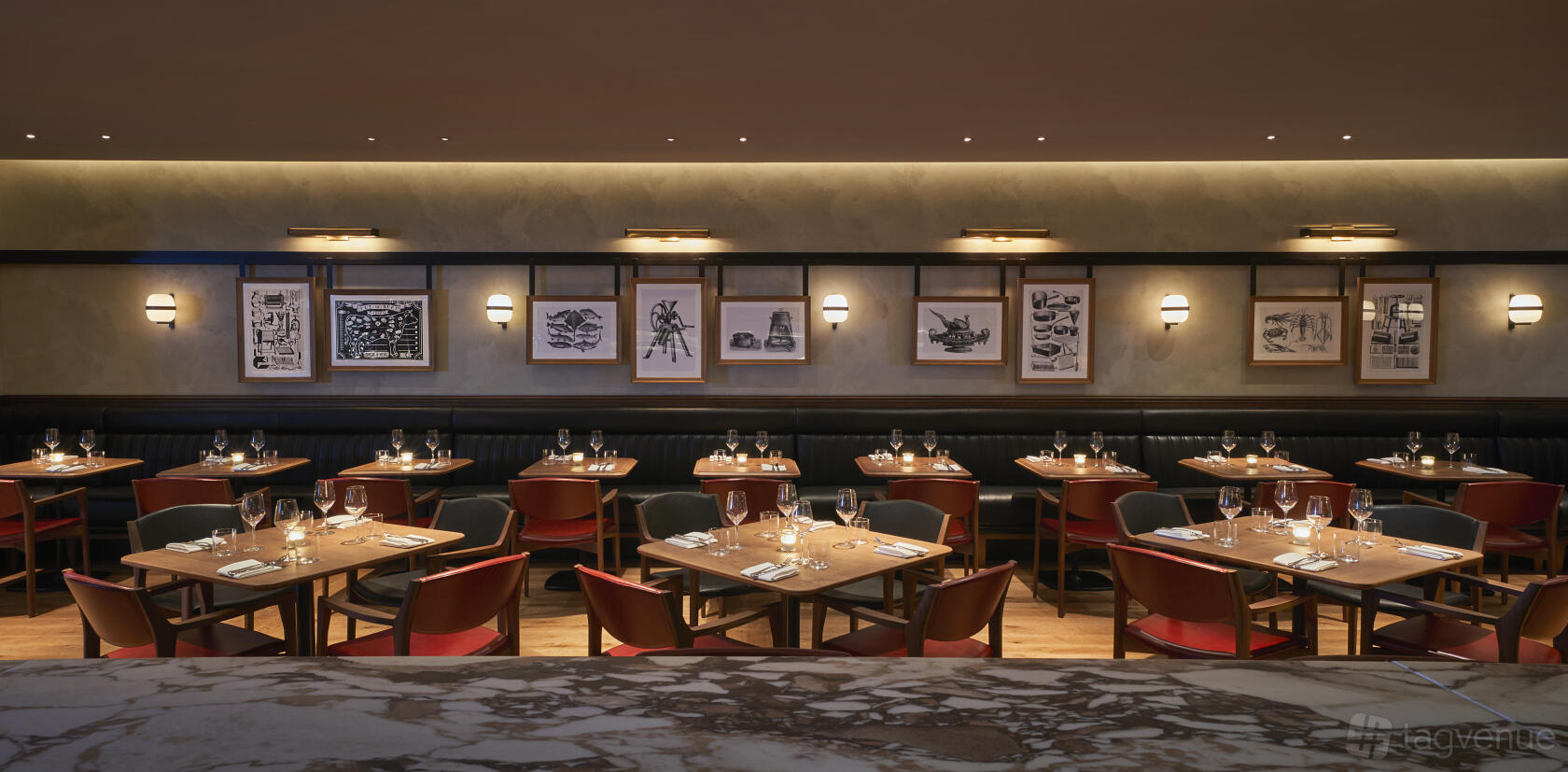 A hotel restaurant with wooden tables, red chairs, banquette seating, and framed artwork on the walls at COMO Metropolitan London.
