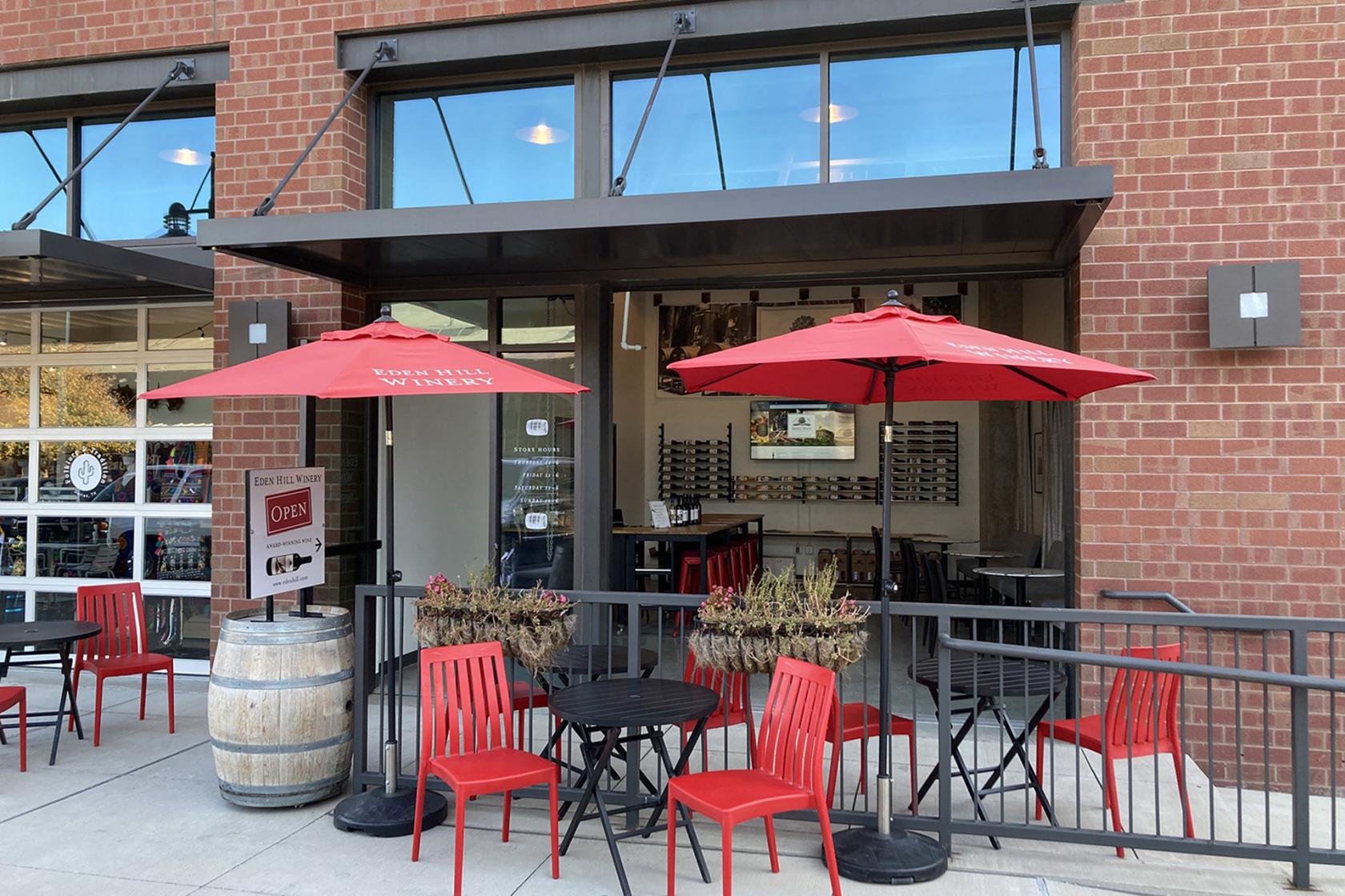 A versatile event space with red patio chairs, wine barrel, and large red umbrellas at Eden Hill Winery at the Dallas Farmers Market.