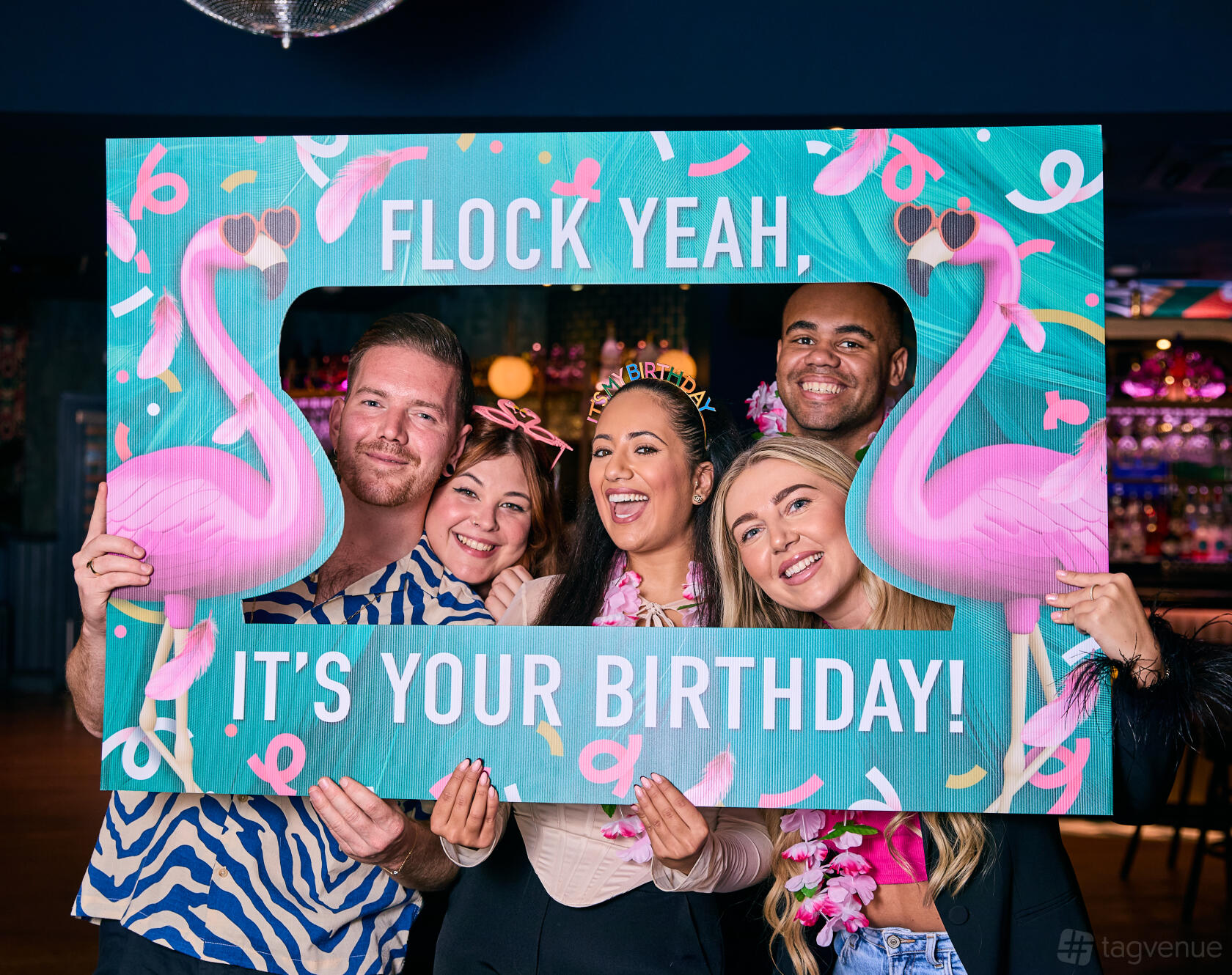 An event space in a bar with neon signage, decorative flamingos, and colorful confetti at Slug and Lettuce Bath.