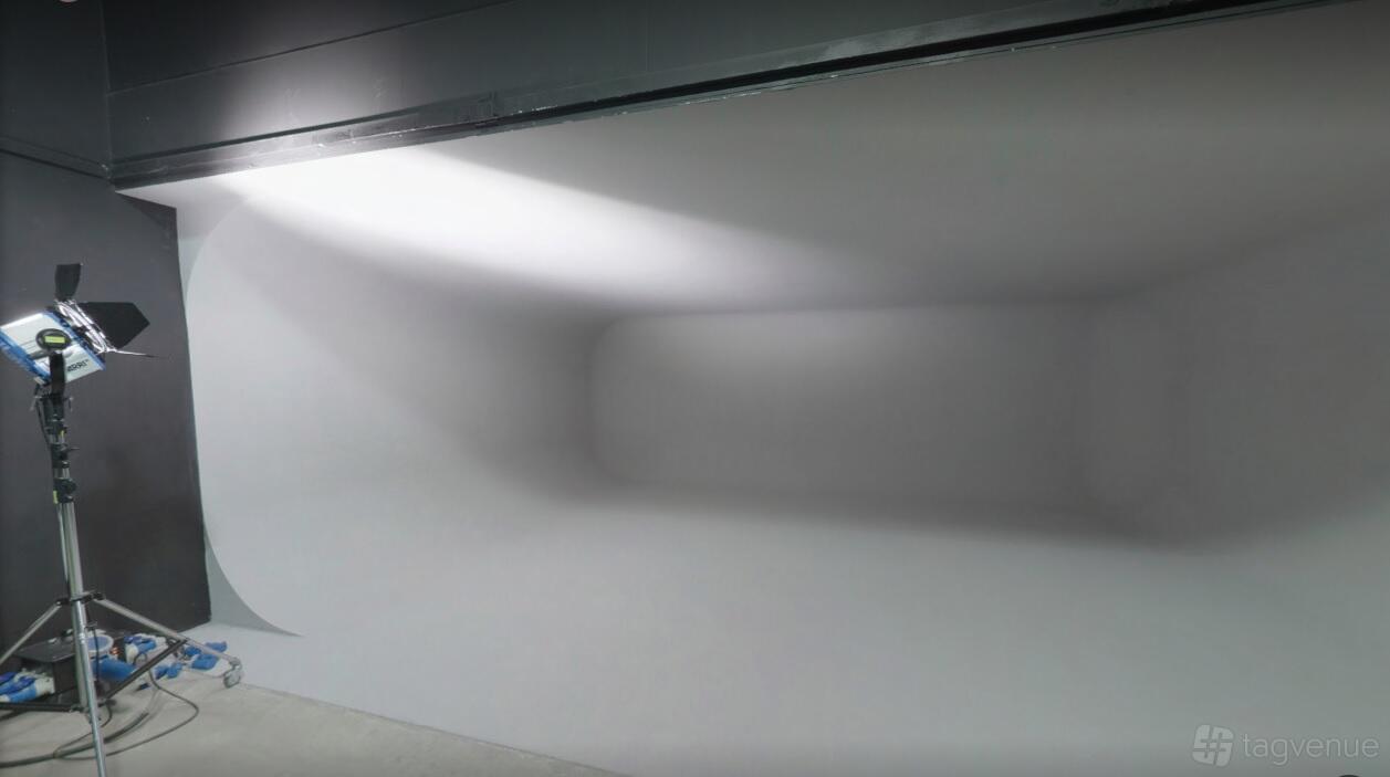 A photo studio with a white cyclorama wall and overhead lighting at Junction Eleven Studios.