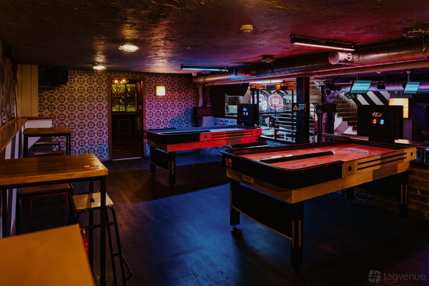 An event space in a bar with shuffleboard tables, industrial lighting, and patterned wallpaper at Roxy Ball Room Leeds Merrion Street.