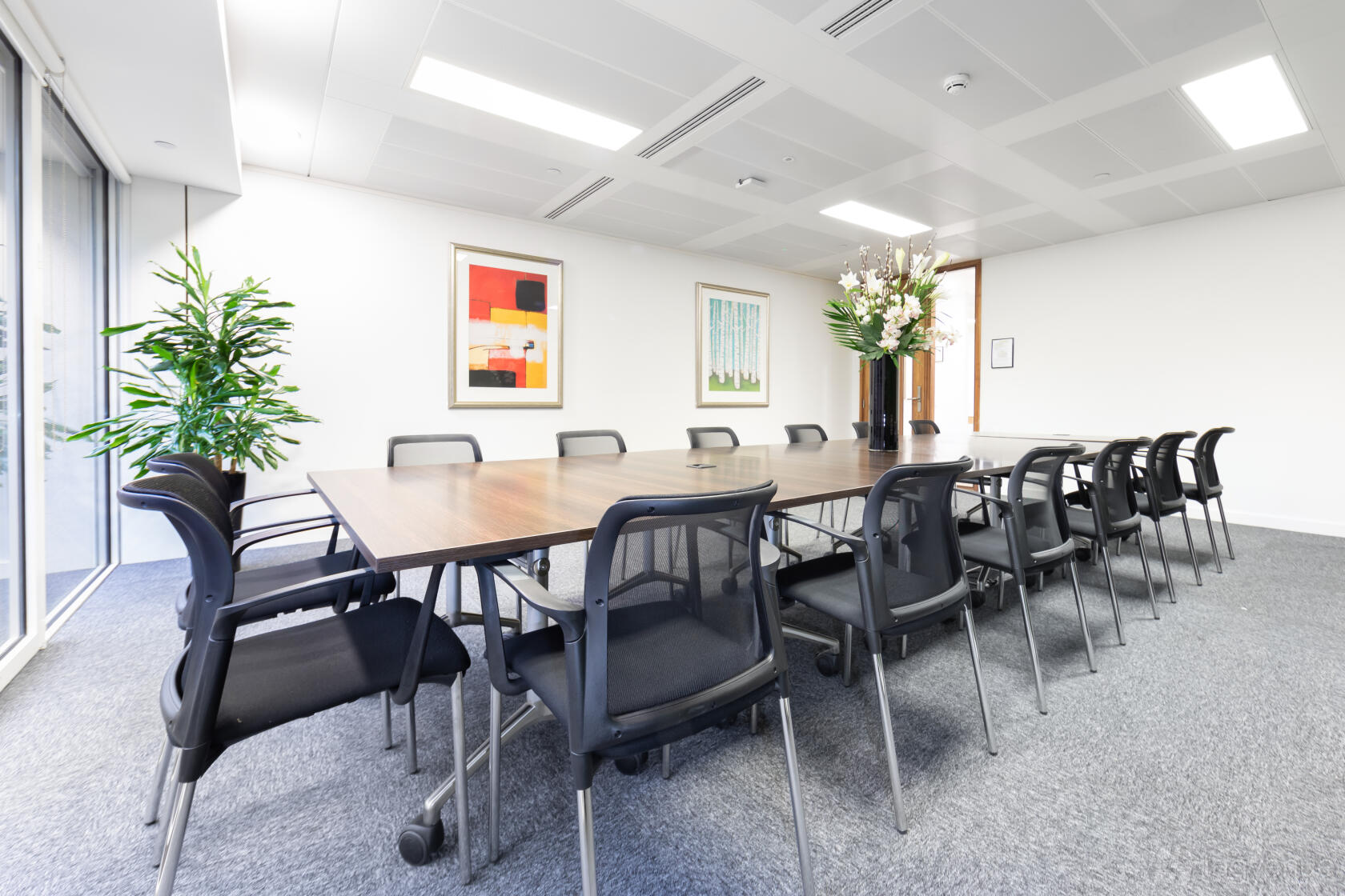 A meeting centre with a long wooden table, black chairs, large framed art, and floor-to-ceiling window at Landmark: King William Street, London.