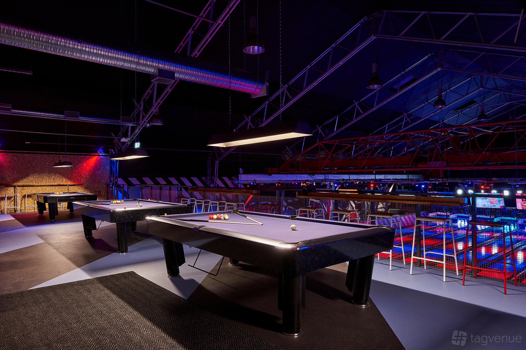 An event space with pool tables, overhead pendant lighting, and exposed beams at Roxy Lanes Birmingham Digbeth.