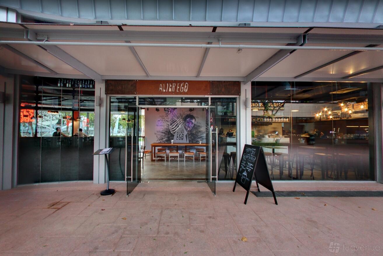 A bar entrance with glass doors, a mural behind wooden tables, and a chalkboard sign at Alter Ego.
