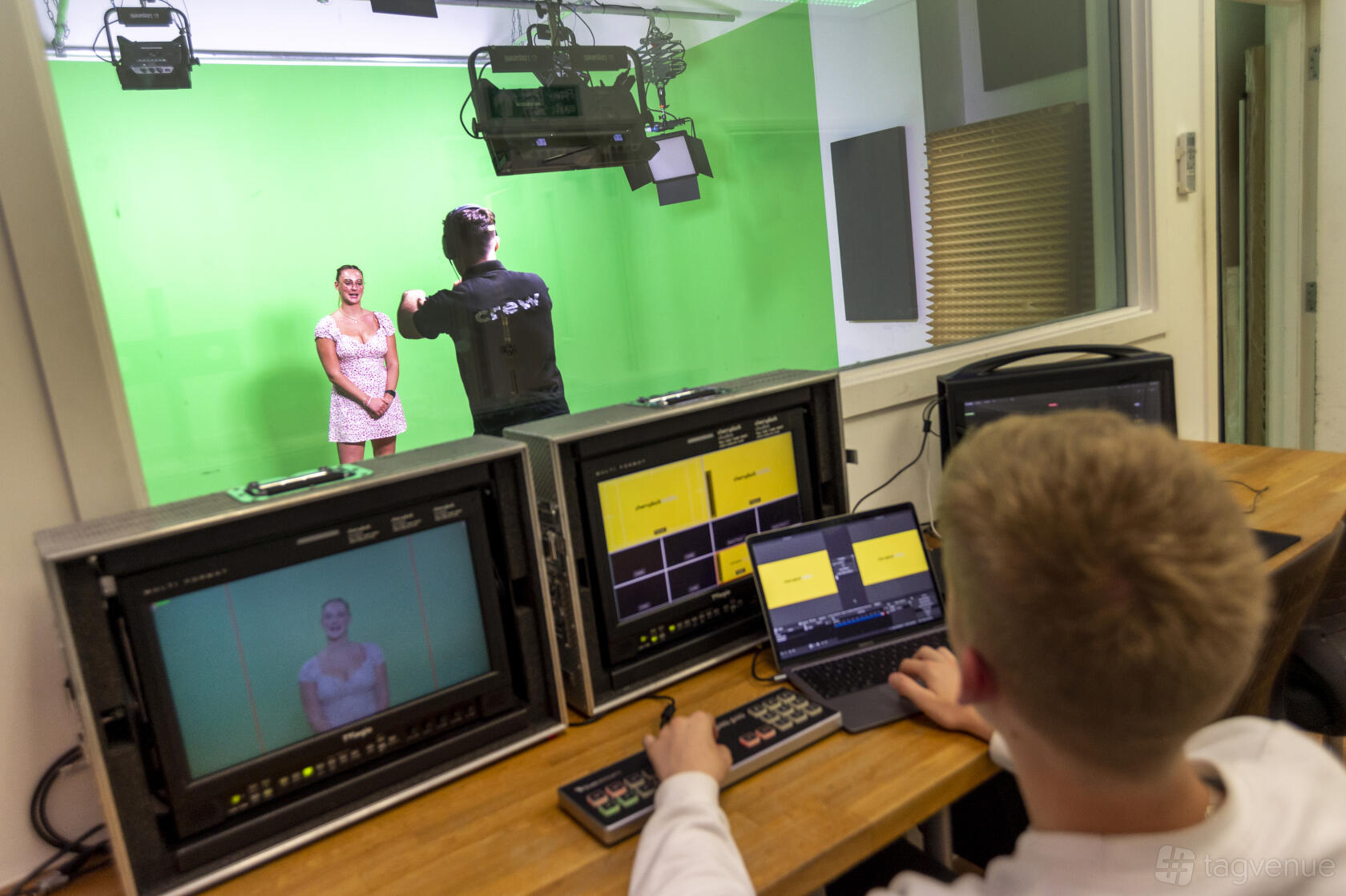 A photo studio with a green screen backdrop and live video monitors in a control booth at Tower Bridge Studios.