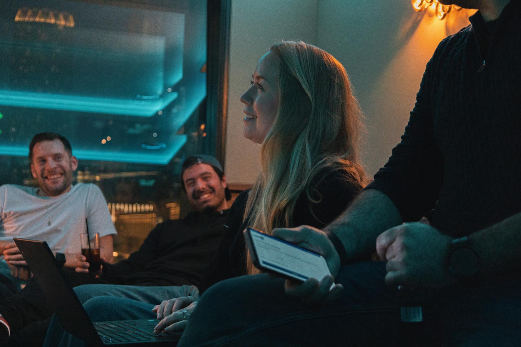 A lounge in a cocktail bar with low lighting, large windows, and plush seating at Qube East - Cocktail Bar & Recording Studios.