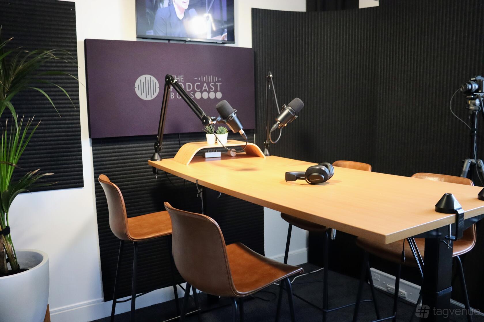 A podcast studio with microphones on adjustable arms, acoustic panels, and leather chairs at The Podcast Boss.