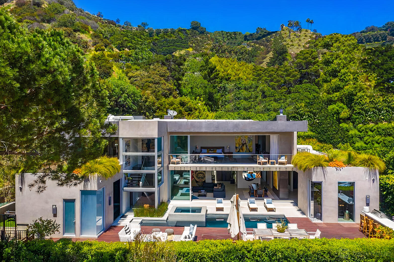 A penthouse with floor-to-ceiling windows, multiple balconies, deck seating, and hillside views at Luxury Villa Above Sunset Strip.