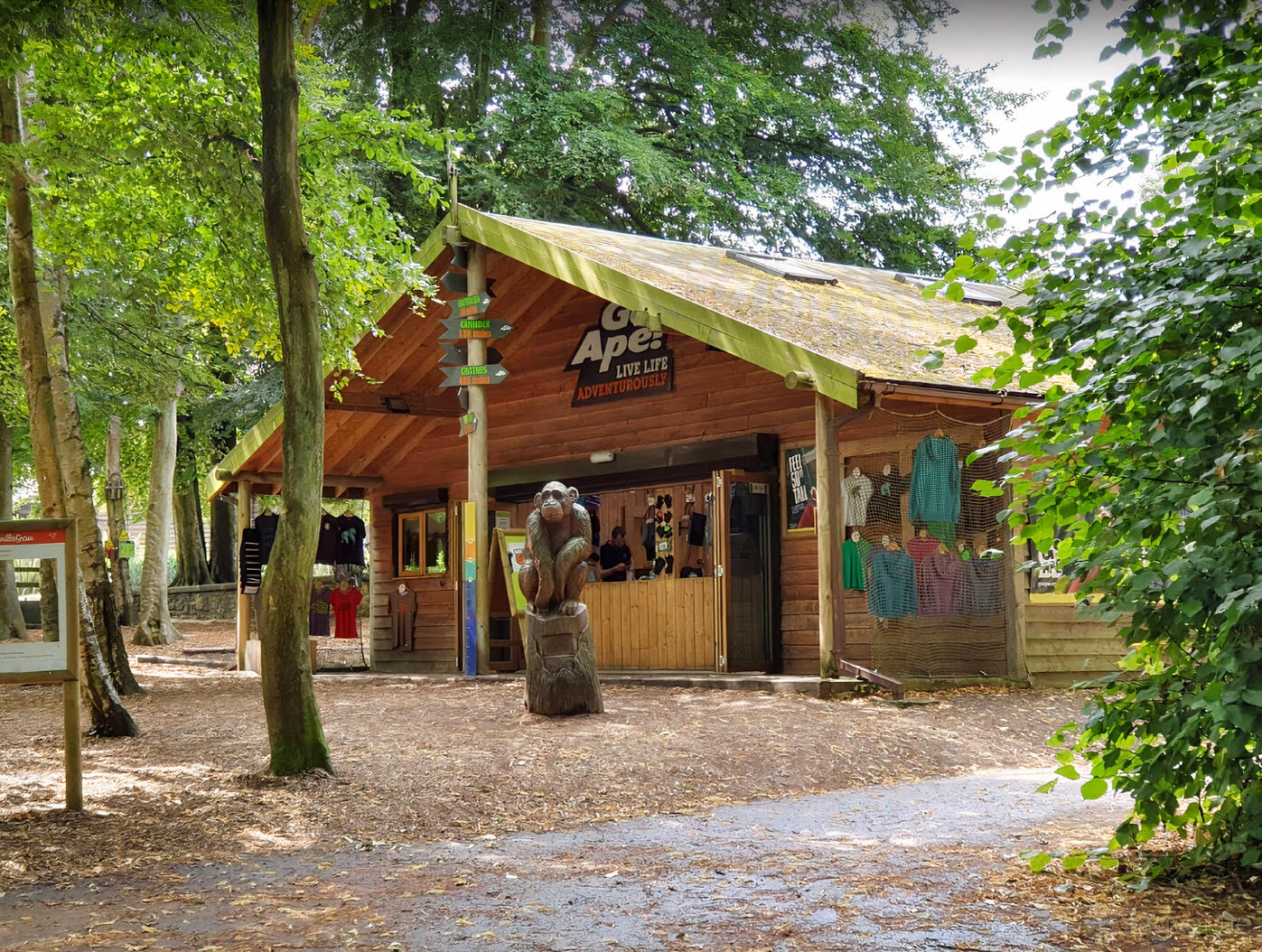 An outdoor venue with a wooden lodge surrounded by tall trees and a carved gorilla statue at Go Ape Crawley.
