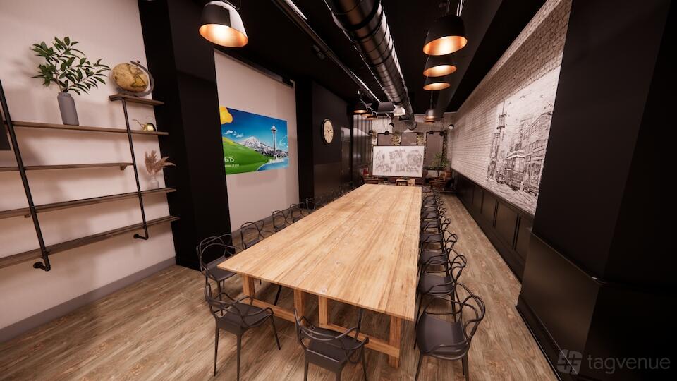 A warehouse venue with a long wooden table, black chairs, exposed ductwork, and wall art at EVNT by LAUFT.