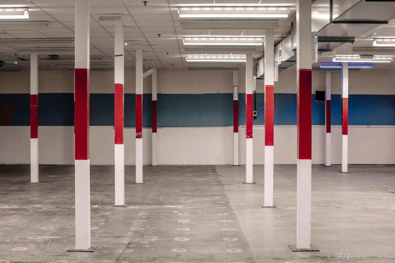An open industrial event venue with exposed support columns and fluorescent lighting at DOCUMENT.