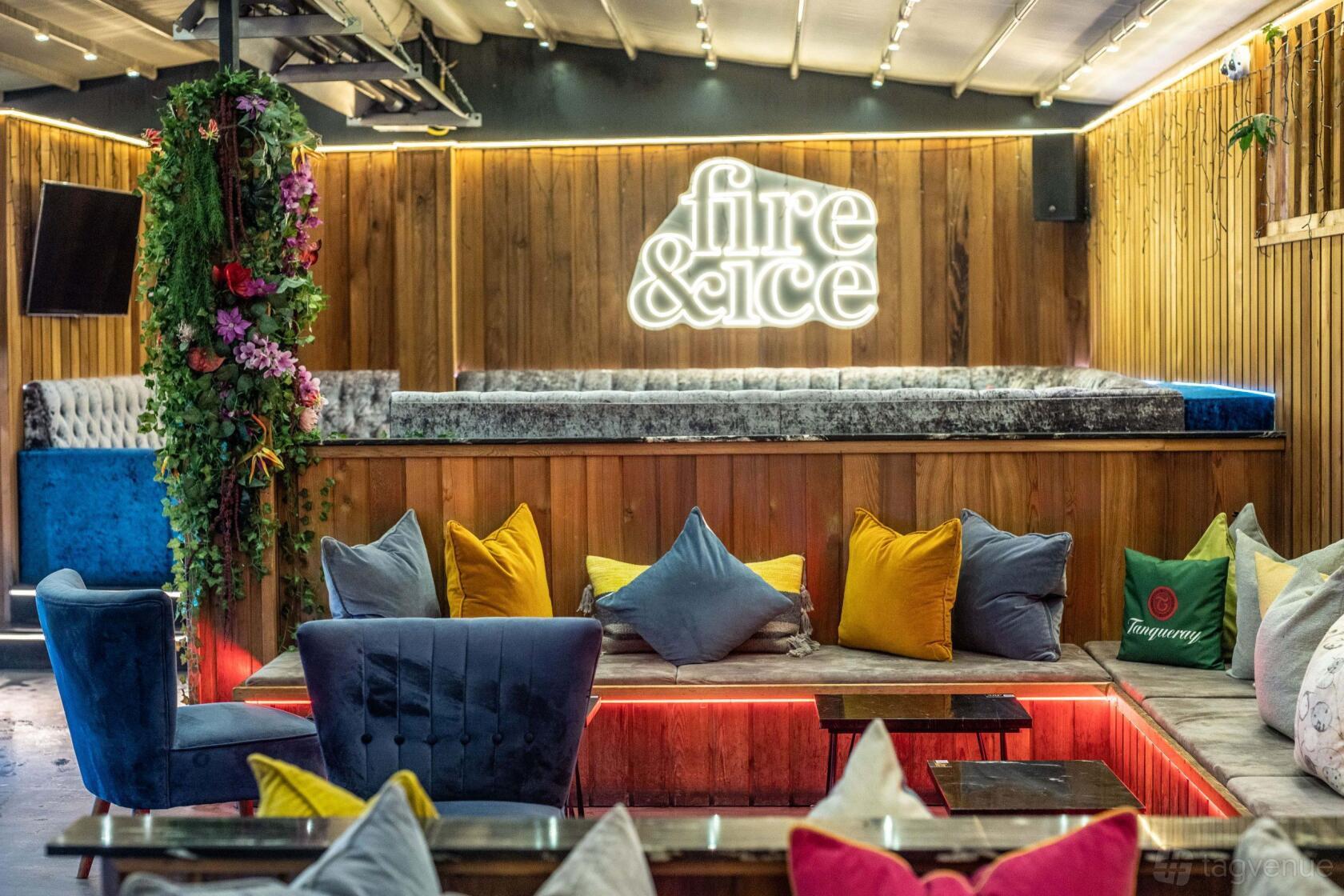 An outdoor lounge with colorful cushions, wooden walls, velvet seating, and neon signage at Fire & Ice Lounge Bar.