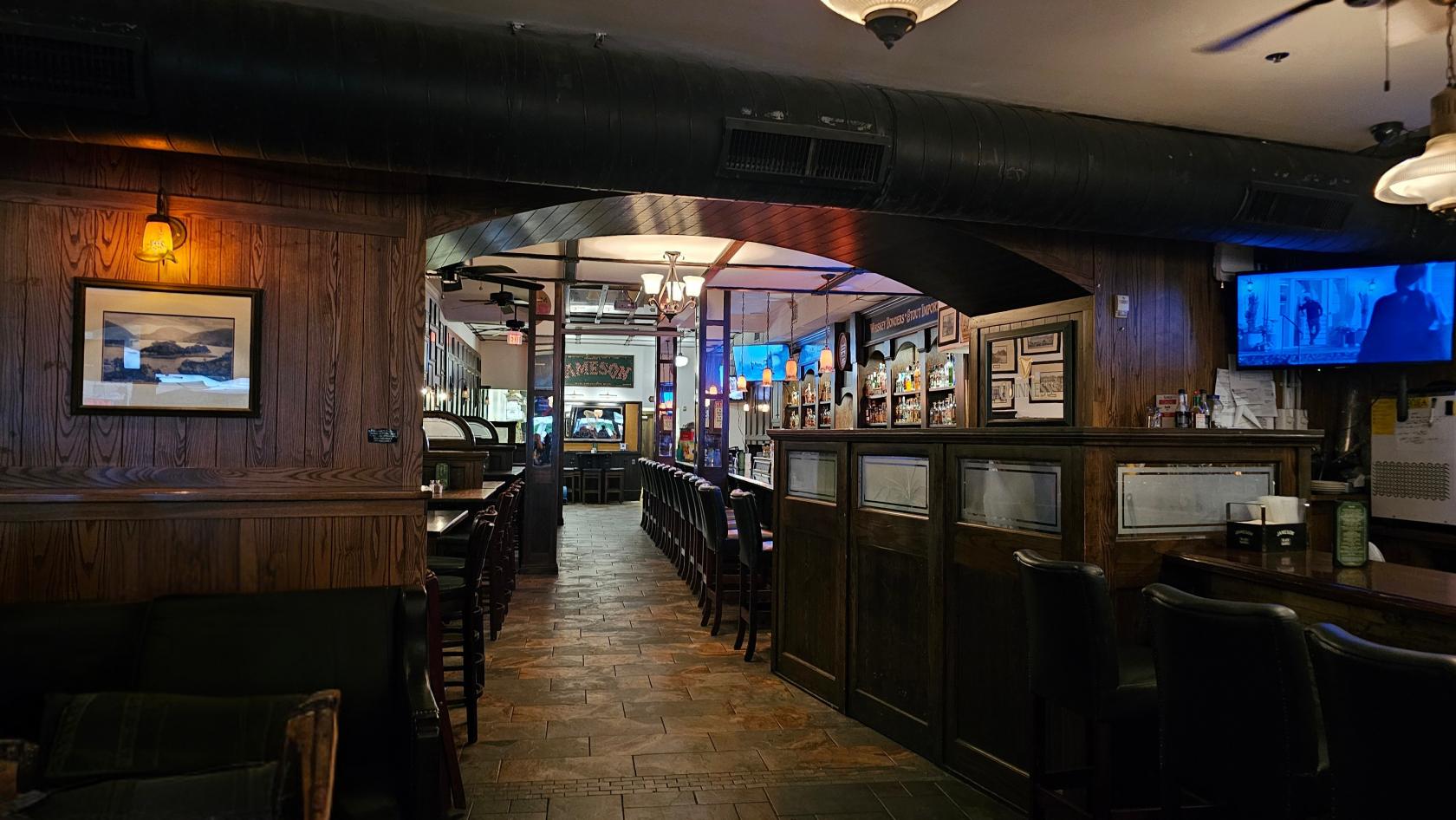A traditional bar with wooden paneling, long bar counter, leather seating, and dim lighting at Waxy O'Connors.