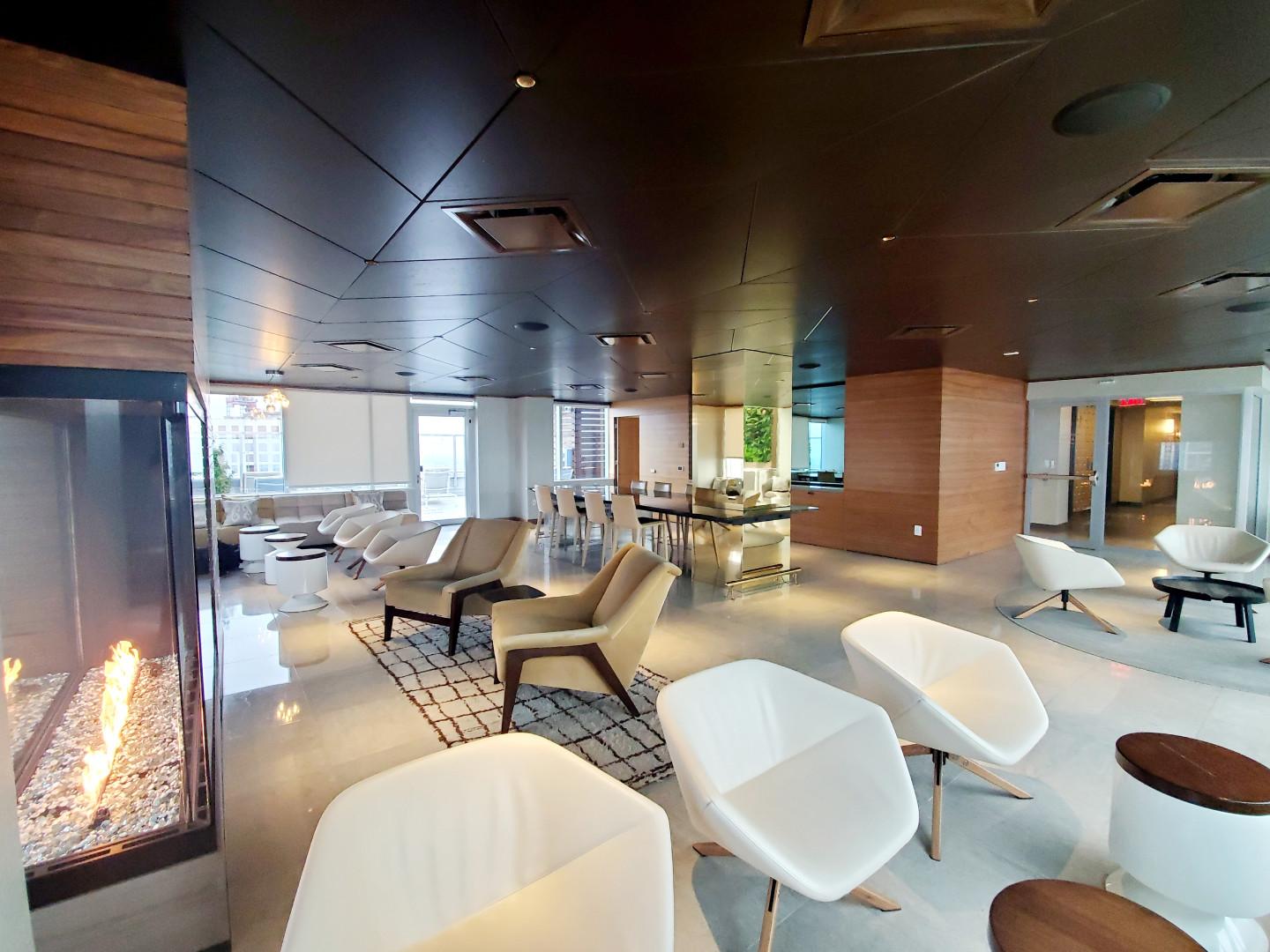 A penthouse with floor-to-ceiling windows, a modern fireplace, and lounge seating at The Sky Lounge.