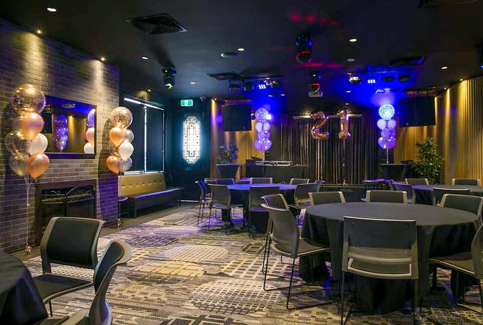 A function room with round tables covered in black linens, patterned carpet, and decorative balloons at Hallam Hotel.
