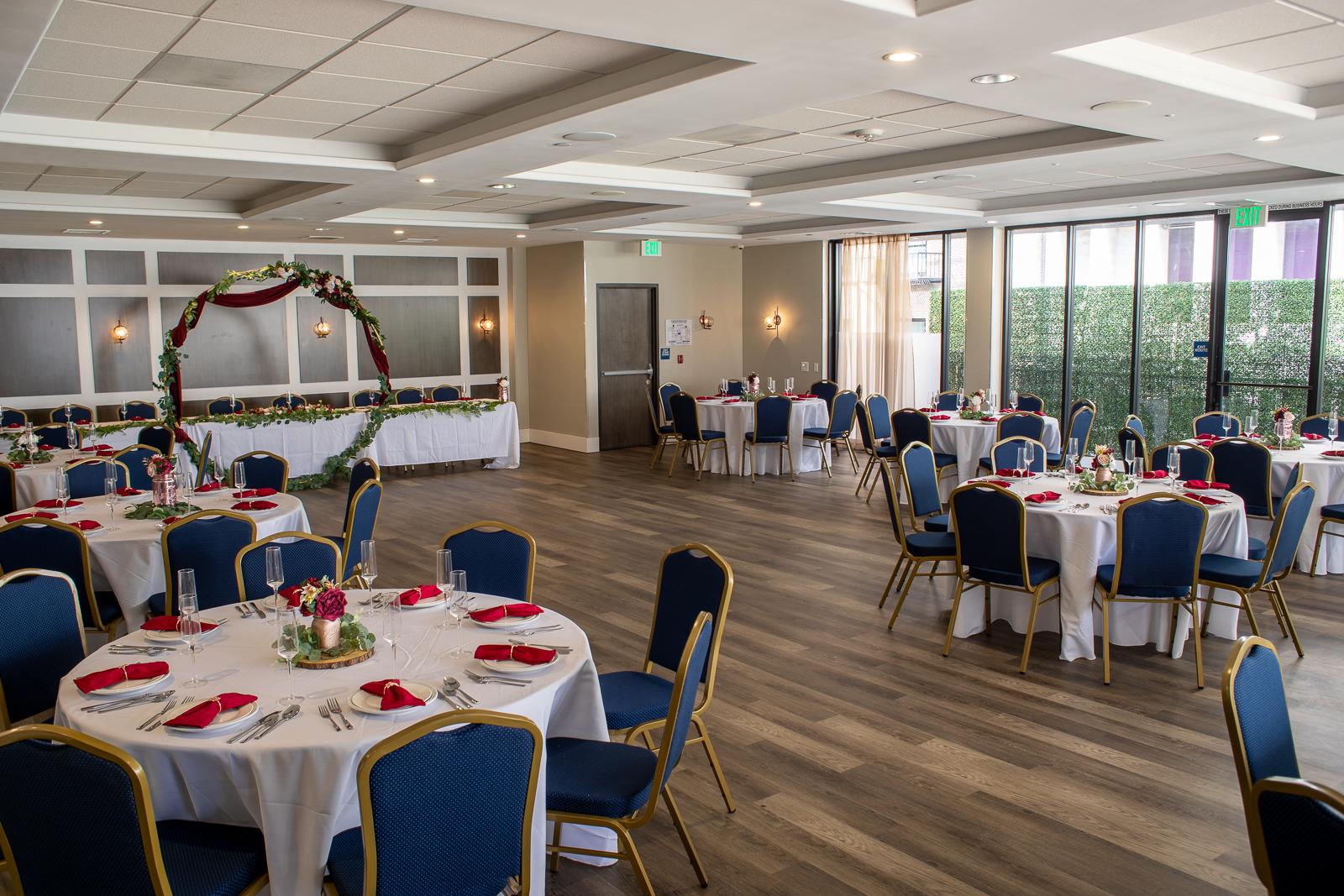 An event venue with round tables covered in white linens, blue chairs, and floral centerpieces at The Top of the Hub.