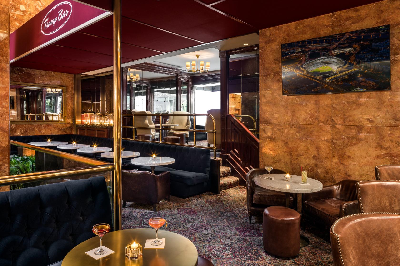 A bar with plush velvet seating, marble-topped tables, mirrored walls, and warm lighting at 45 Wine & Whiskey Bar.