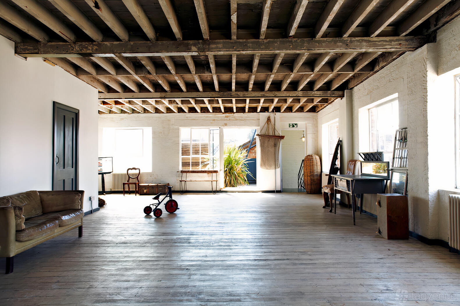 A warehouse with exposed wooden beams, whitewashed brick walls, and large windows at Friendly Place.