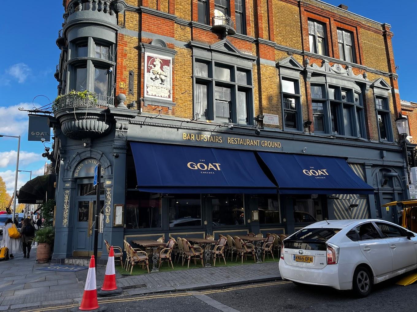 A restaurant terrace with outdoor bistro tables and chairs lining the sidewalk at The Goat Chelsea.