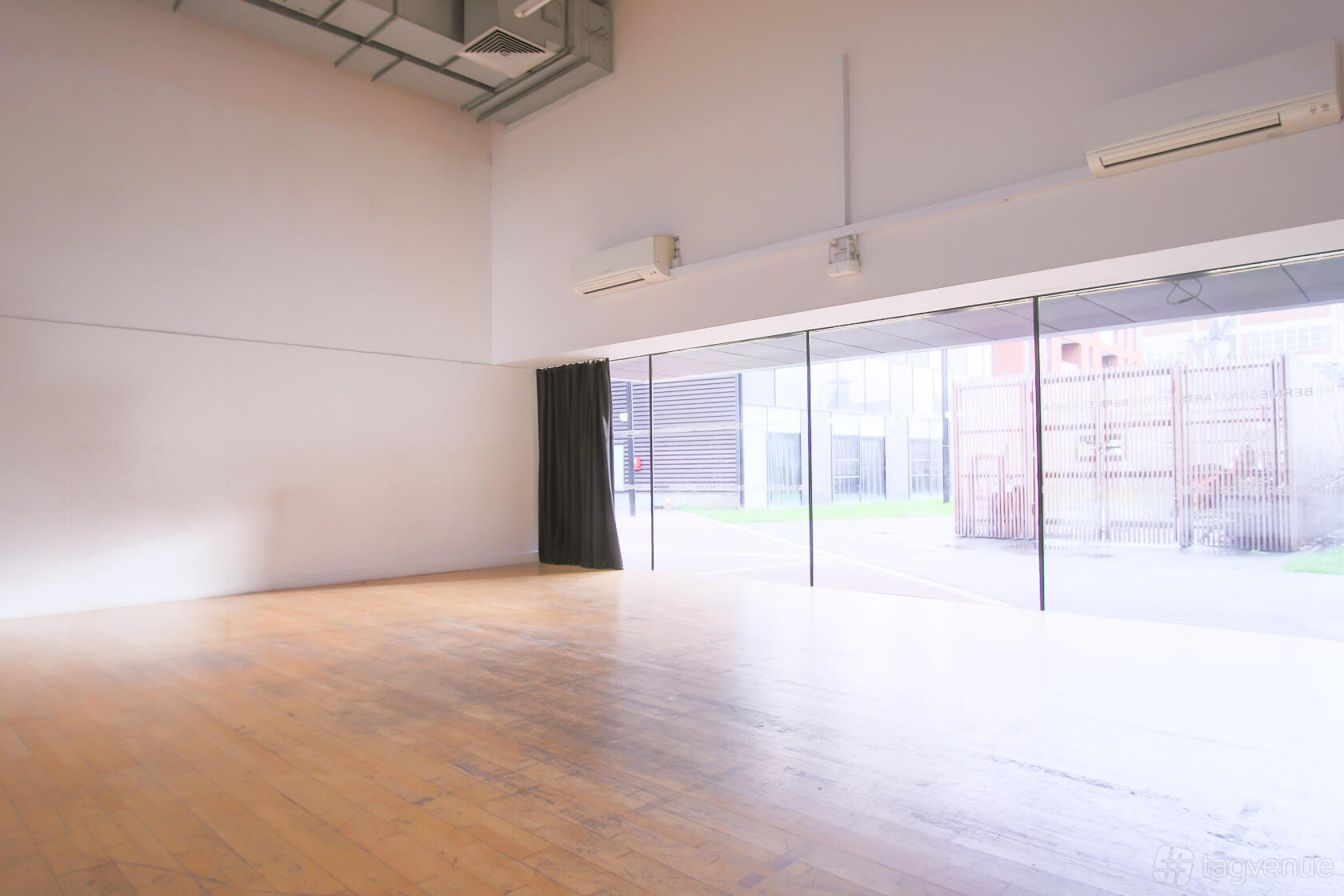 An event venue with floor-to-ceiling windows, light wood flooring, and high ceilings at Bernie Grant Arts Centre.