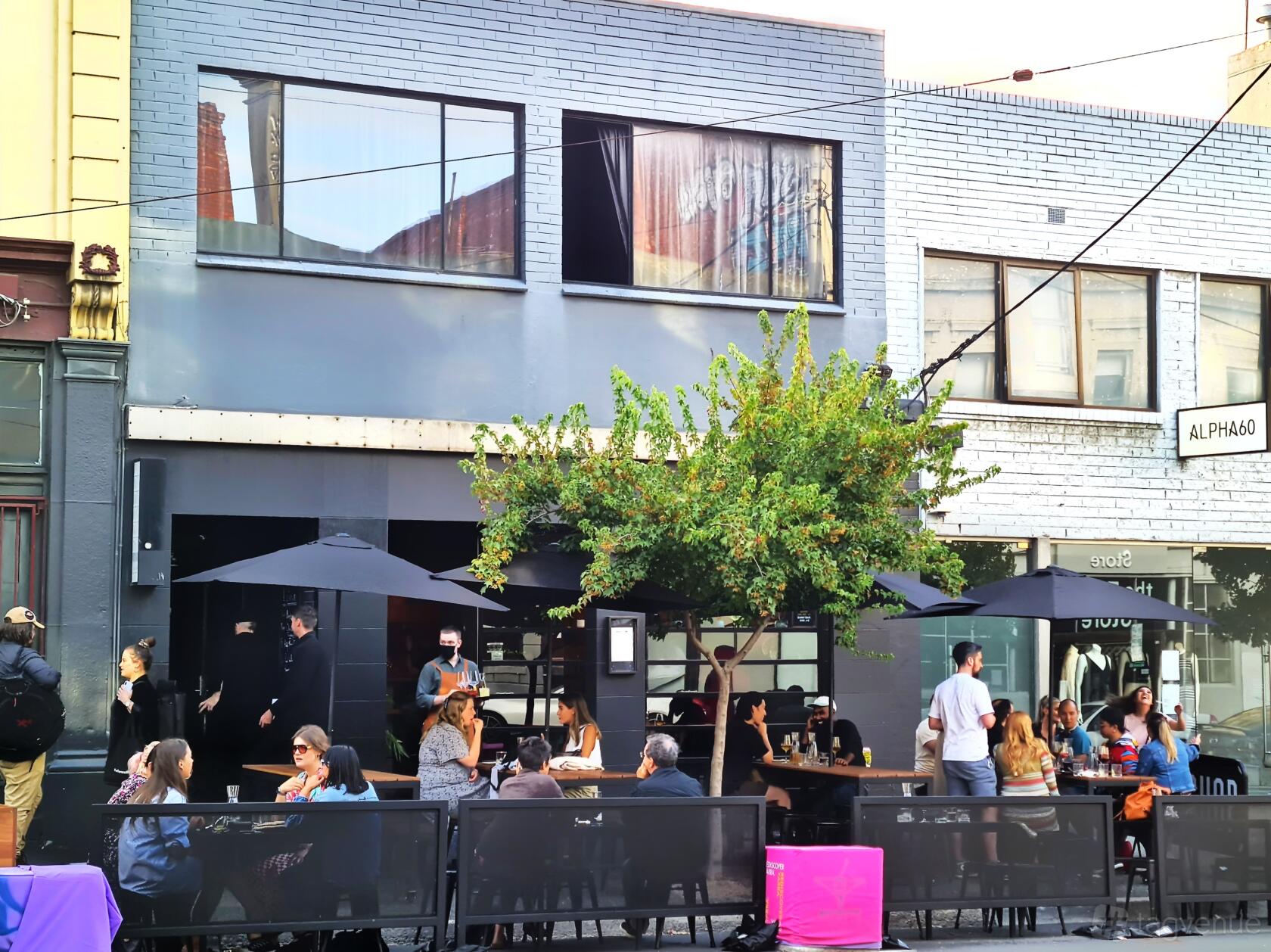 A bar with an outdoor seating area, black umbrellas, and street-facing tables at Bonny.