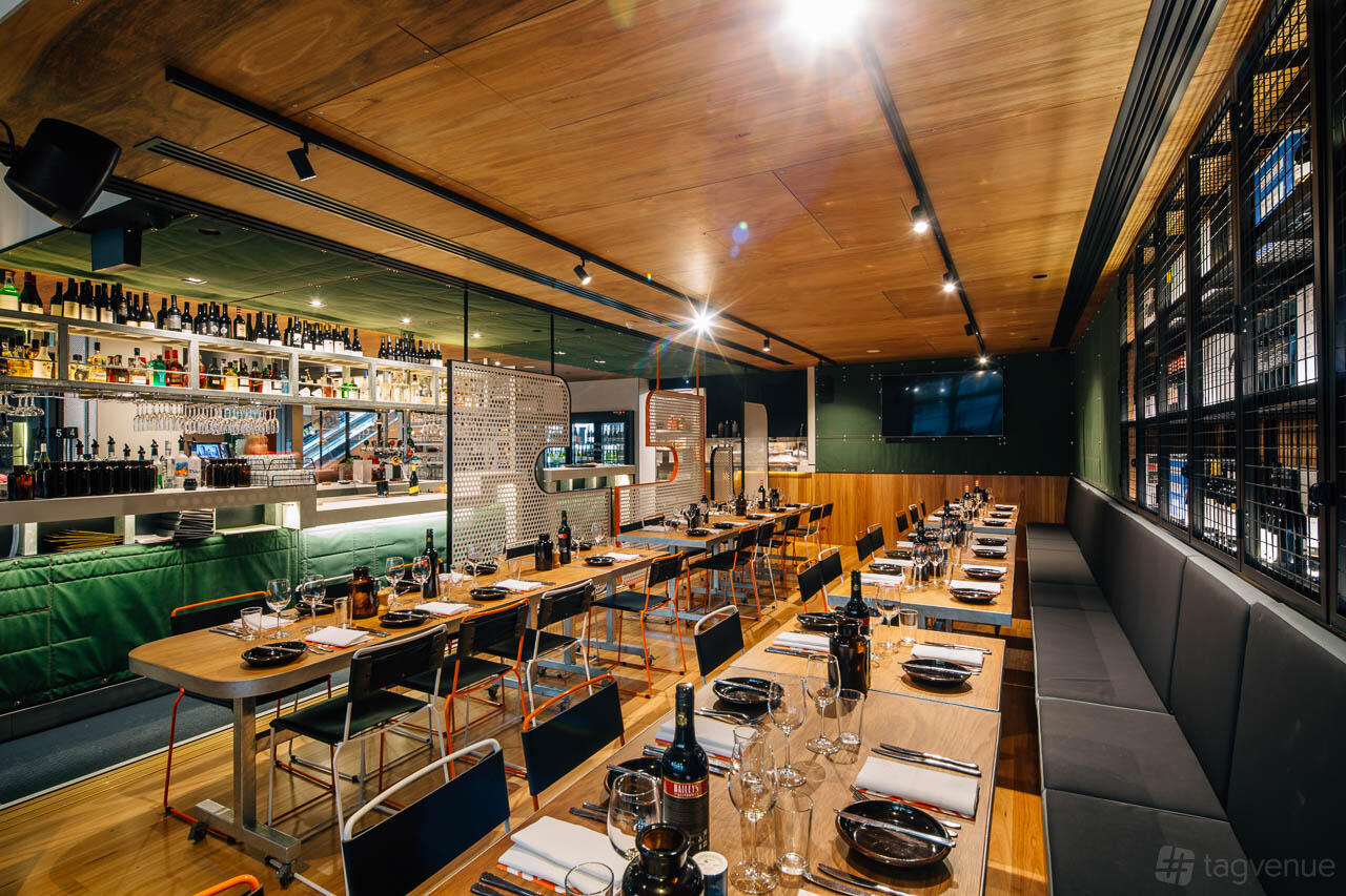 A dining room with wooden tables, metal chairs, wine bottles, and an open shelving bar at BearBrass.