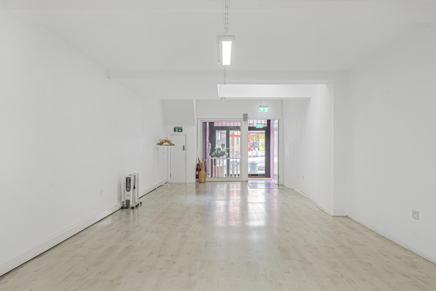 An event venue with light wood floors, white walls, and large front windows at Stokey Popup.