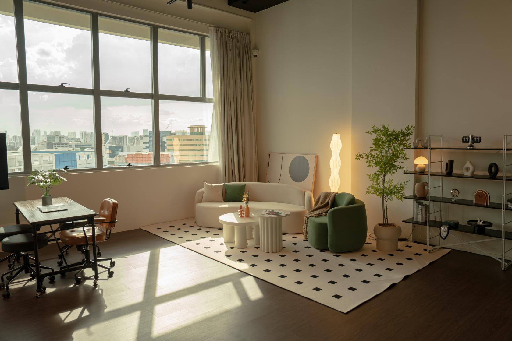 A photo and film studio with large windows, natural light, a lounge area, and minimalist decor at Studio11 by The Studio Clan.
