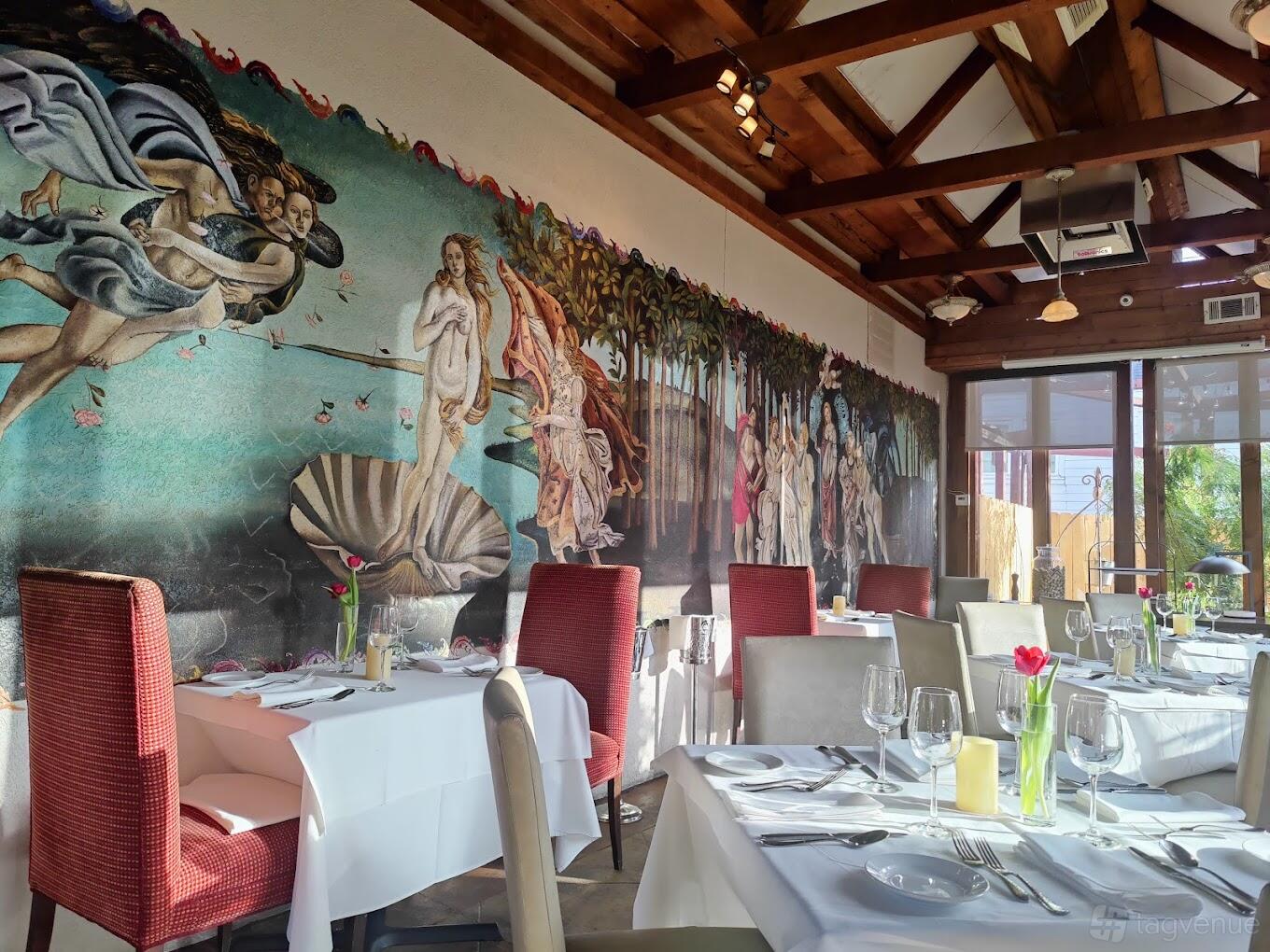 A function room in a restaurant with a large Renaissance mural, exposed beams, and tables set with white linens at Sorrento.