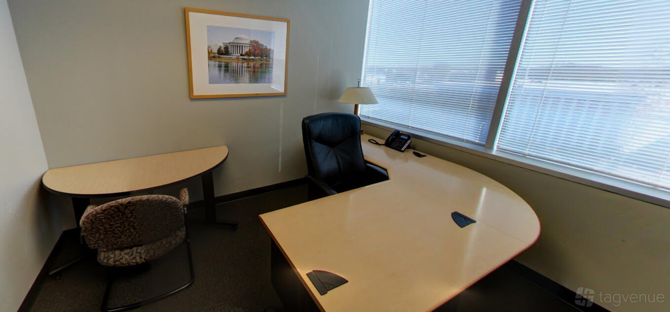 An office space with large corner desk, black executive chair, desk lamp, and framed wall art at Intelligent Office in Rockville, MD.