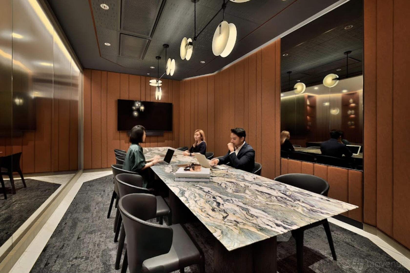 A meeting room with a marble conference table, padded wall panels, and pendant lights at The Great Room - Afro Asia.