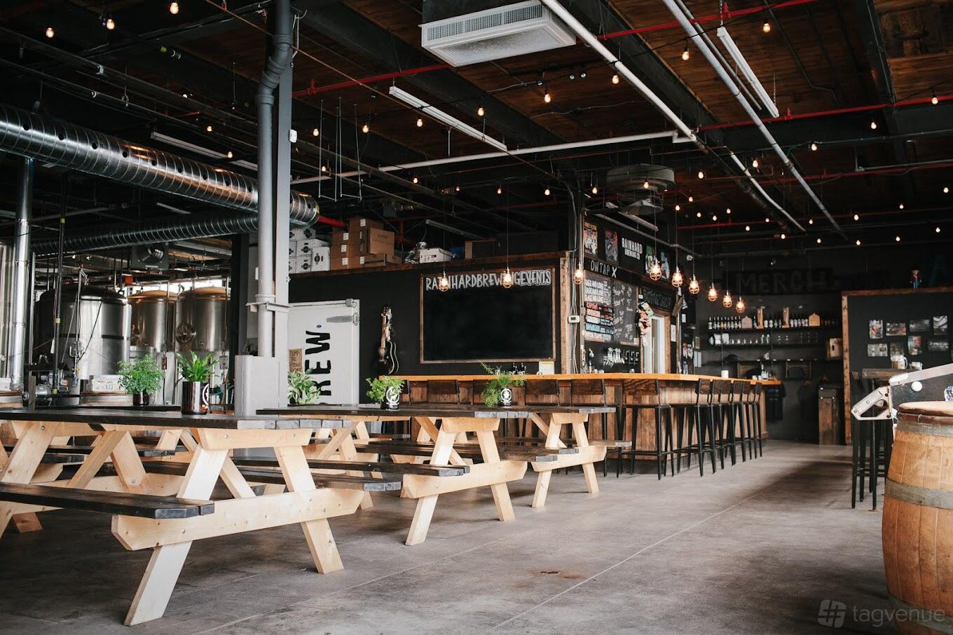 A brewery taproom with wooden picnic tables, hanging string lights, and an open bar at Rainhard Brewing Co.