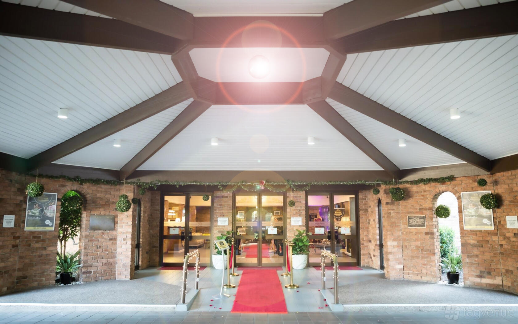 An event space entrance with a red carpet, glass doors, brick walls, and a covered portico at Windsor Function Centre.