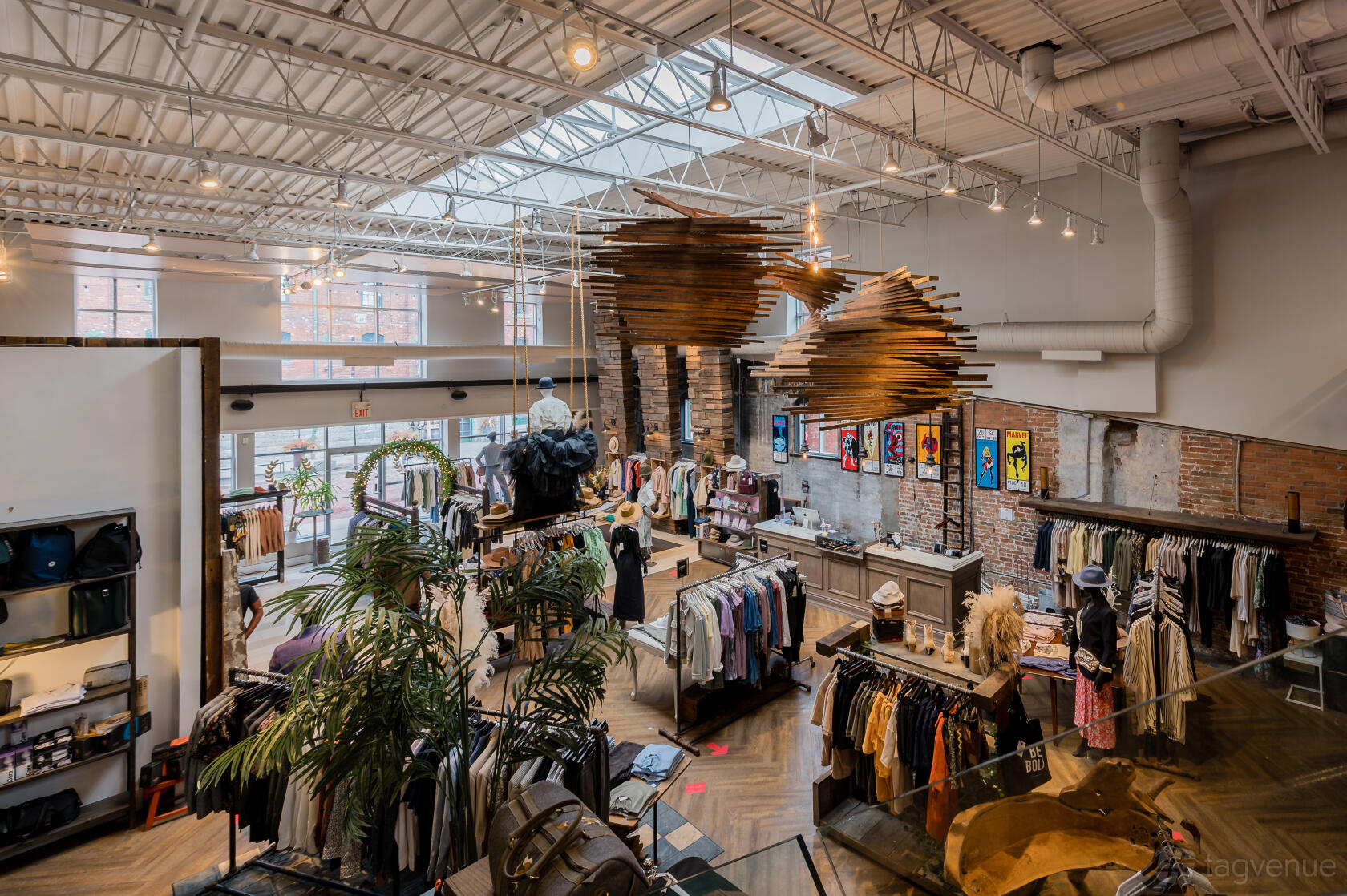A pop up shop in an event venue with exposed brick walls, skylights, and clothing racks at Gotstyle Distillery.