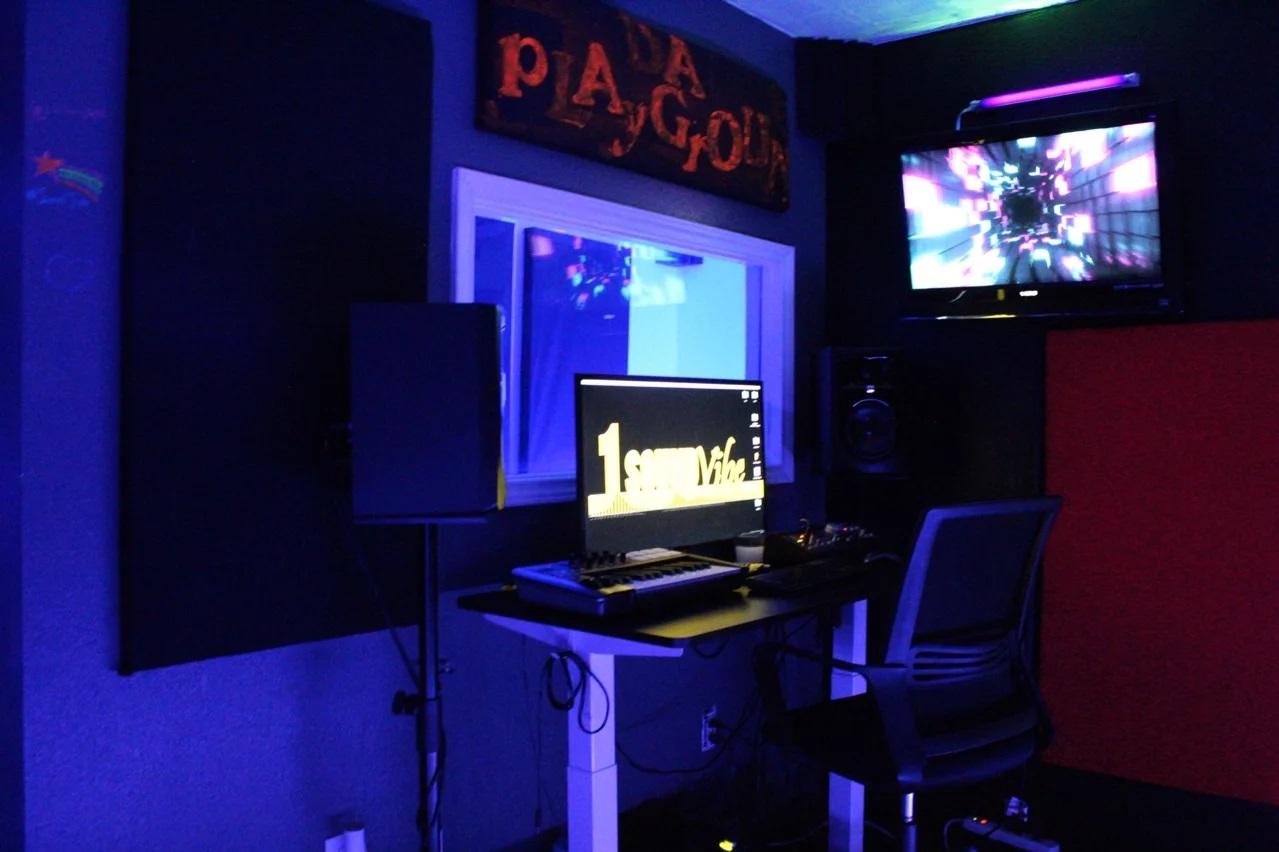 A recording studio with a mixing desk, computer monitors, speakers, and soundproofed walls at 1 SoundVibe Studios.
