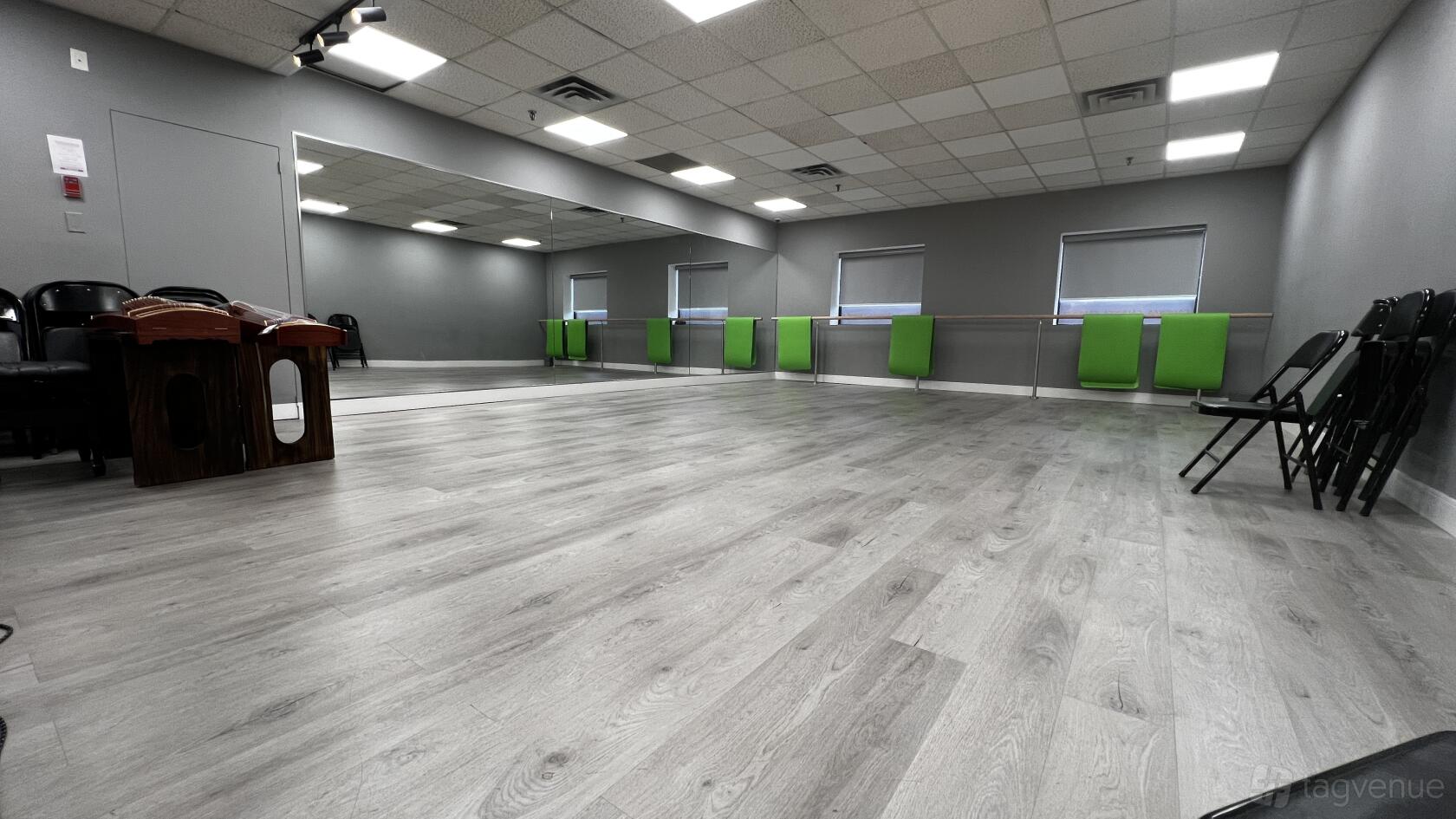 A dance studio with floor-to-ceiling mirrors, ballet barres, and laminate wood flooring at Cadenza pianos.
