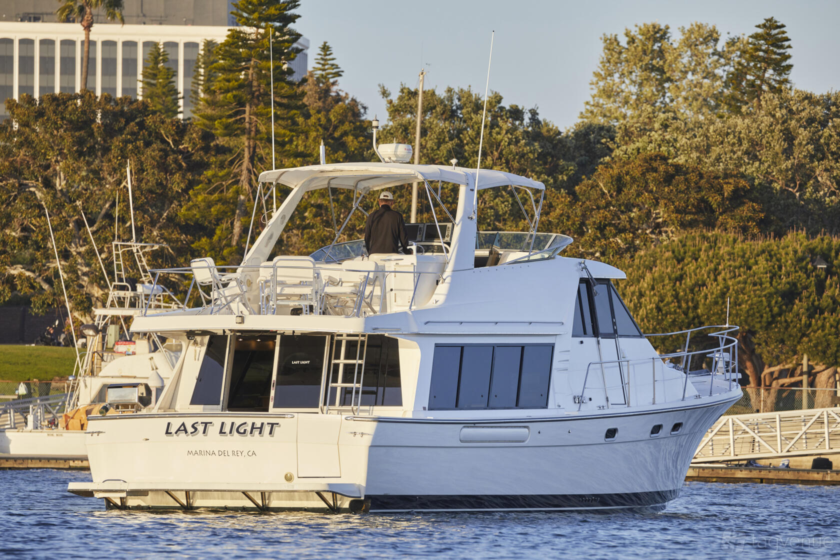 A white boat with an open upper deck and seating areas on the water at Parties at Sea.