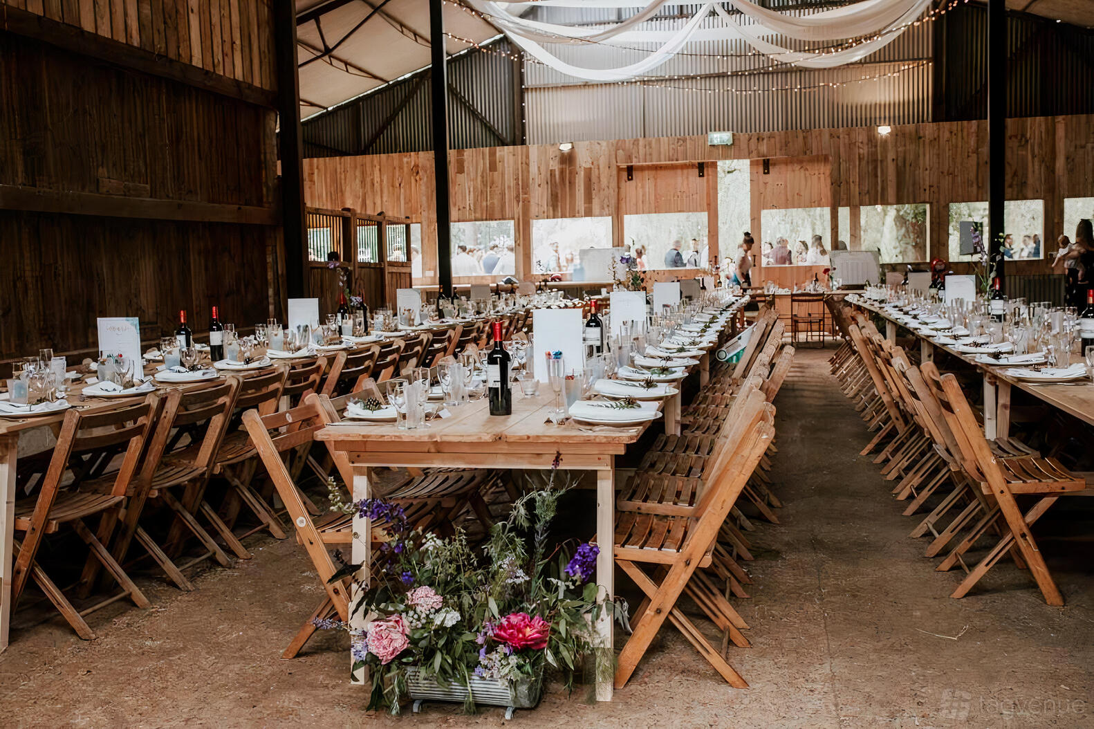 An event venue with long wooden banquet tables, folding chairs, and rustic wood walls at Happy Valley.